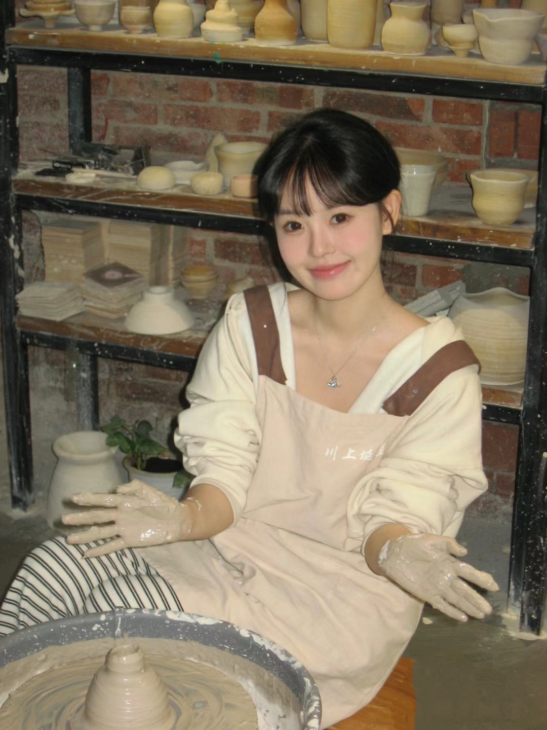 😊白色的工作服显得非常专业,双手沾满棕色的粘土,但并不在意