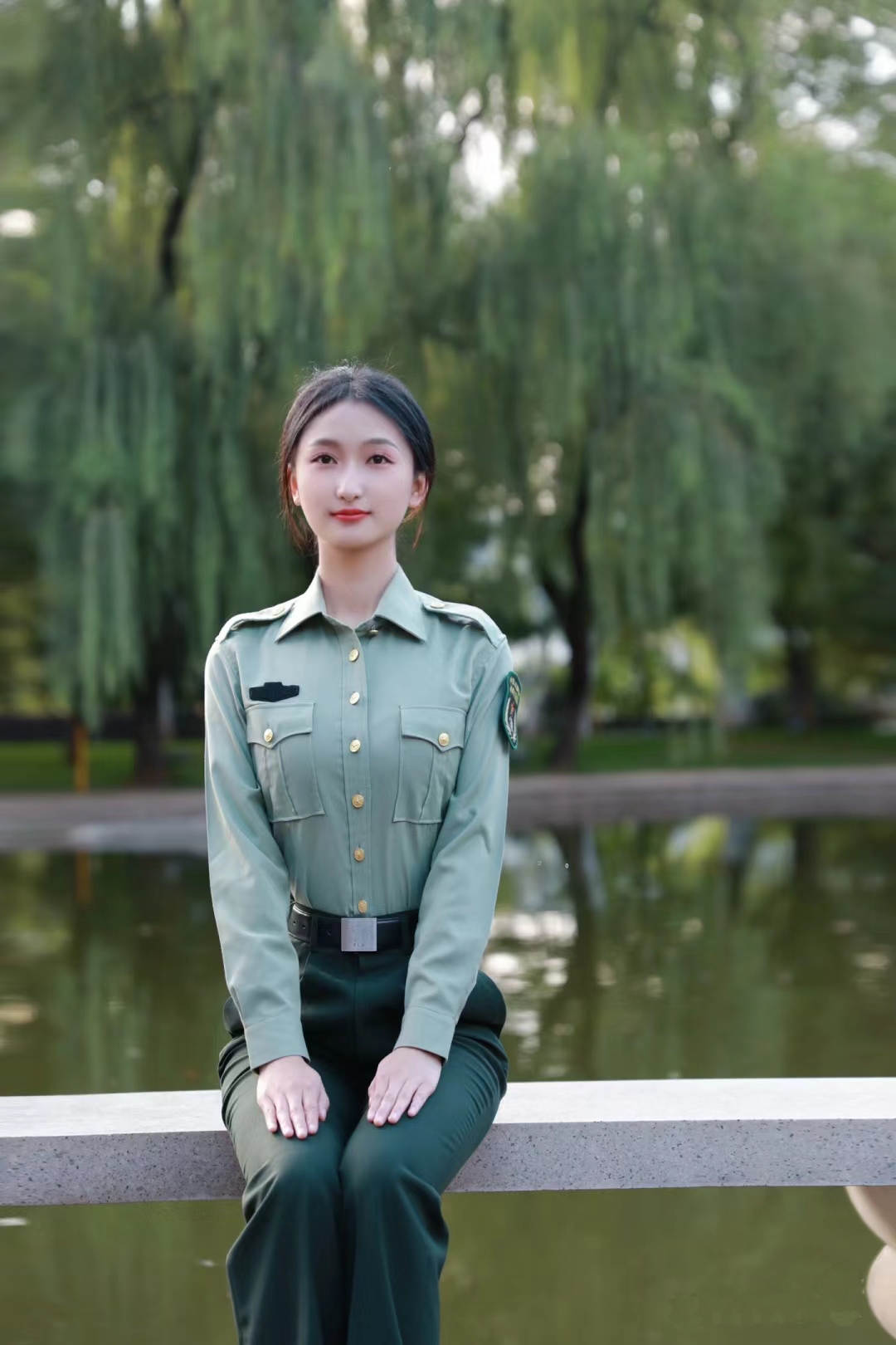 身穿绿色军装的女性,她面带微笑,坐在栏杆上
