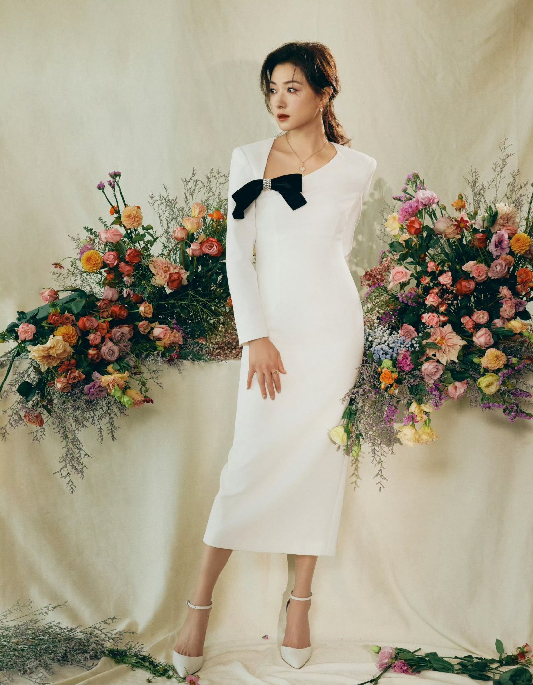 万茜身穿一袭白裙,优雅地站在花团锦簇中,仿佛花仙子降临,美得让人