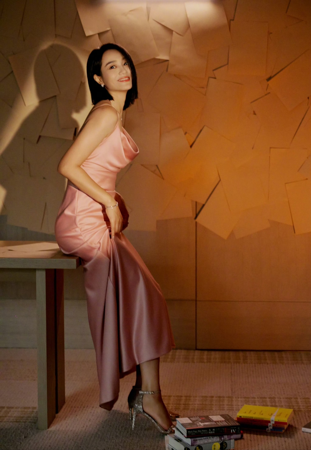 朱丹优雅地倚靠在桌边,身着一袭粉嫩长裙,姿态从容,仿佛从故事中走出