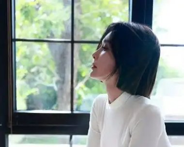 单手撑脸,姿势随意,紧身长裙勾勒出完美身形,裙摆开叉稍露长腿,身材