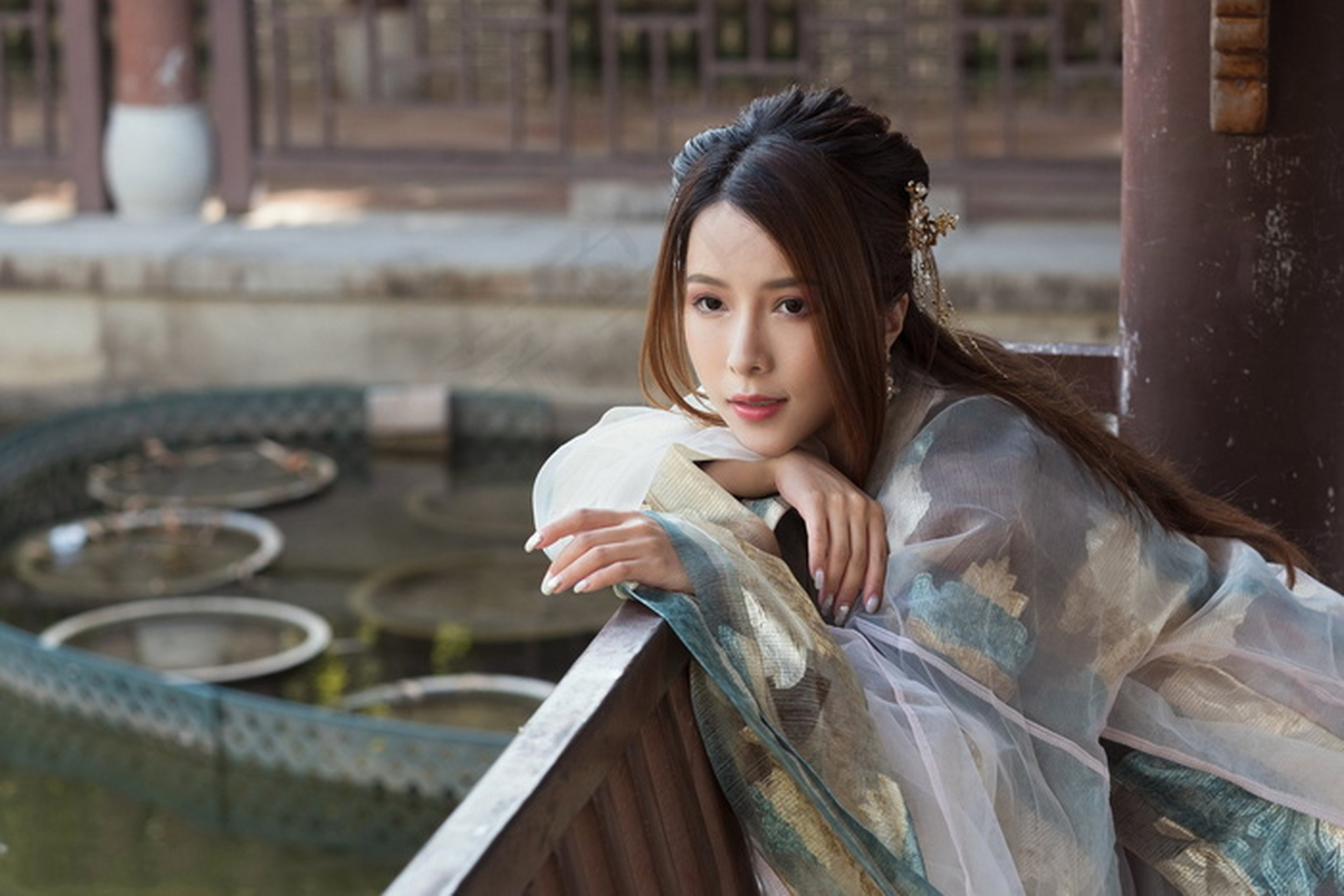 倚石栏之畔,一女子古装临风,秀发如瀑,垂至腰间.