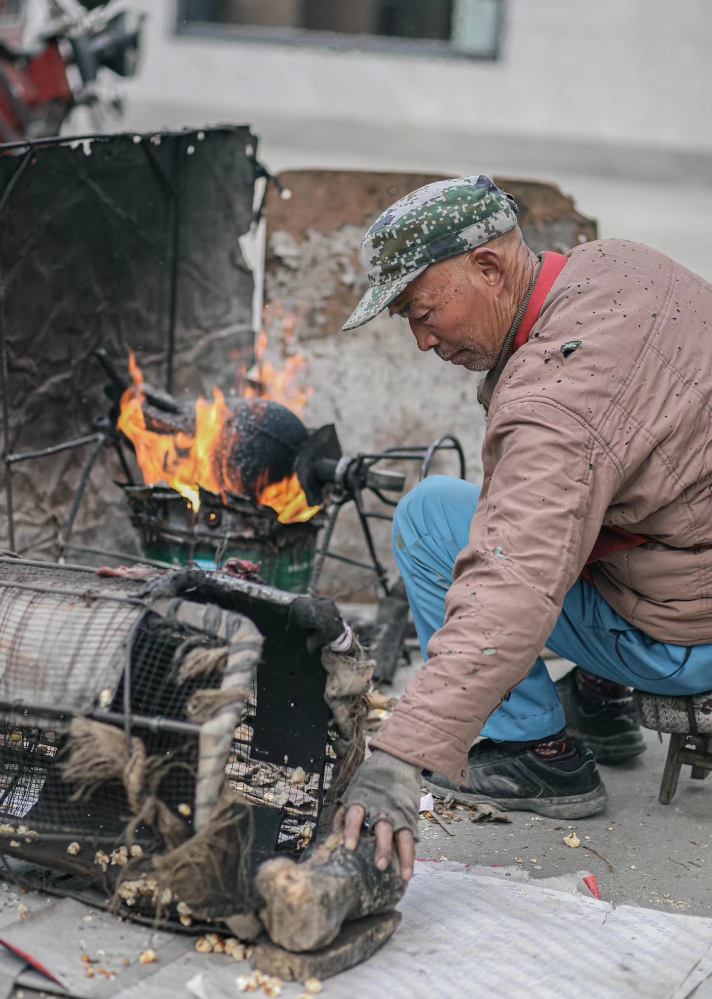街头爆米花摊前,师傅转动着圆锅,不紧不慢地摇着把手