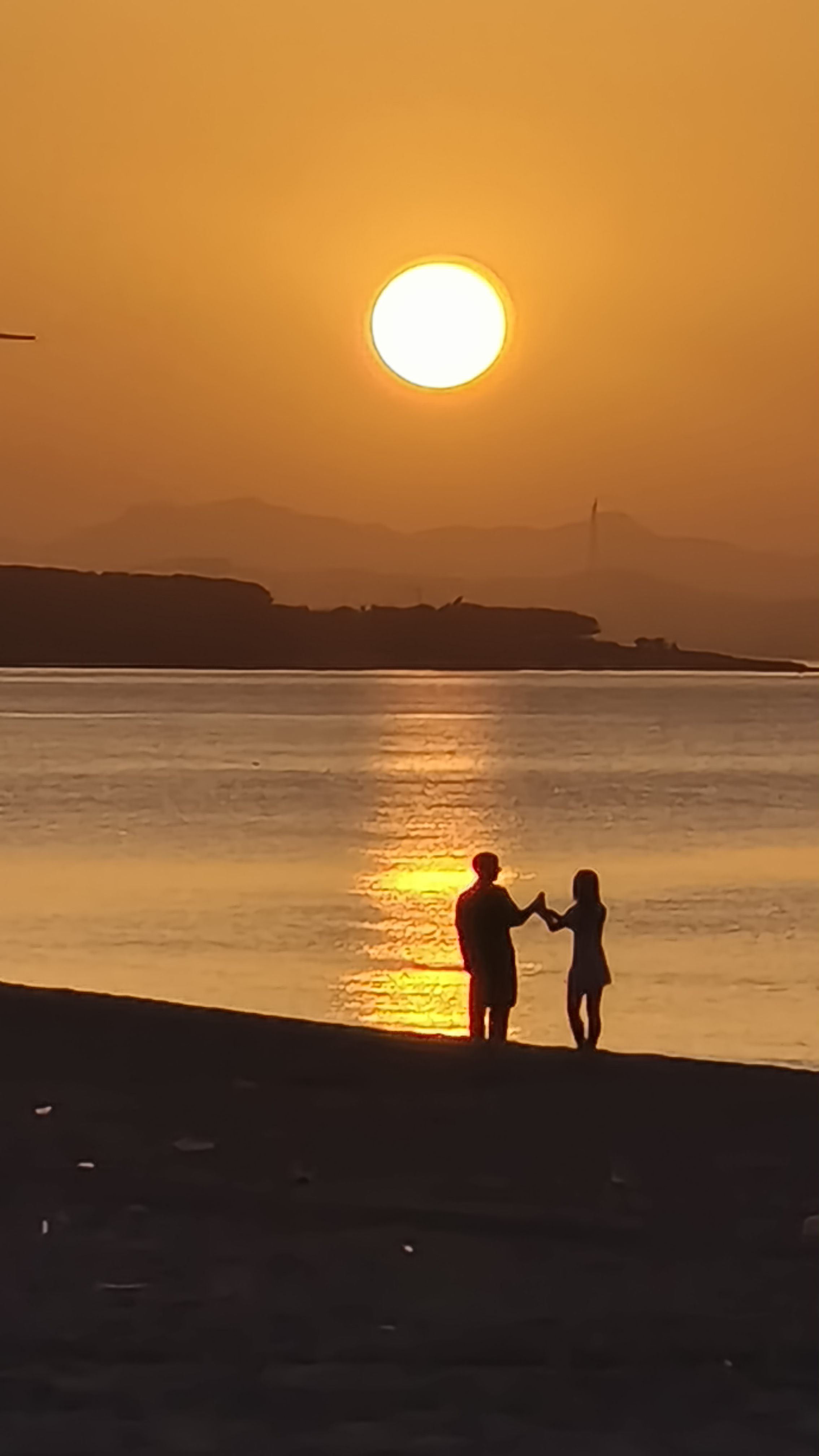 夕阳西下,救生塔下的人们享受着难得的宁静时光,或交谈,或凝望远方