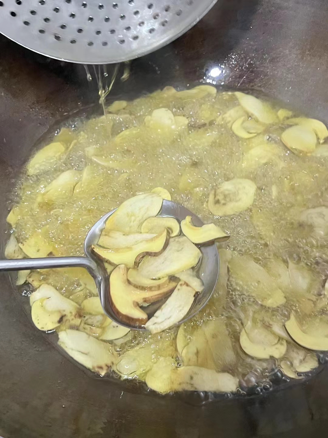 油锅里炸着金黄的蘑菇片,滋滋作响,香气扑鼻.
