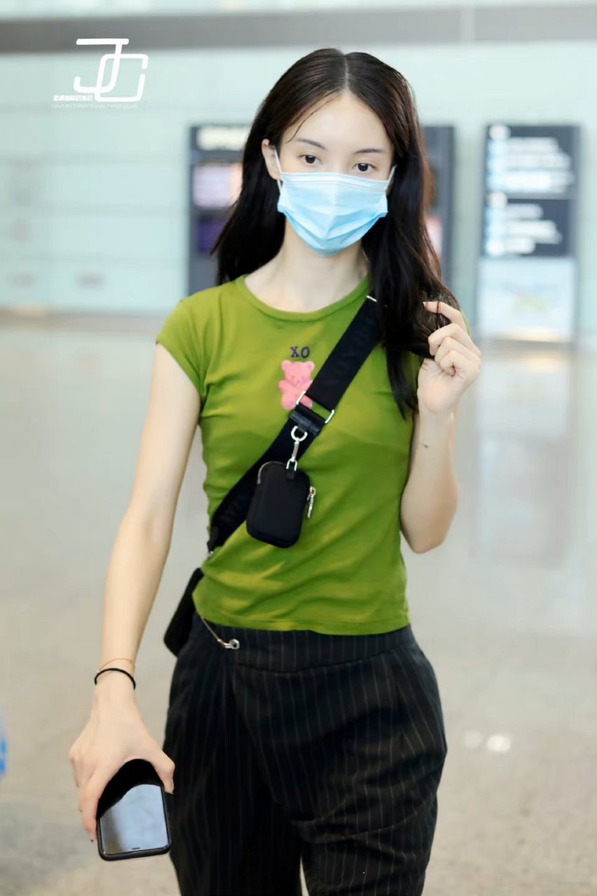 金晨绿色牛油果修身t恤搭配深色条纹休闲裤和白色运动鞋,背着黑色单肩