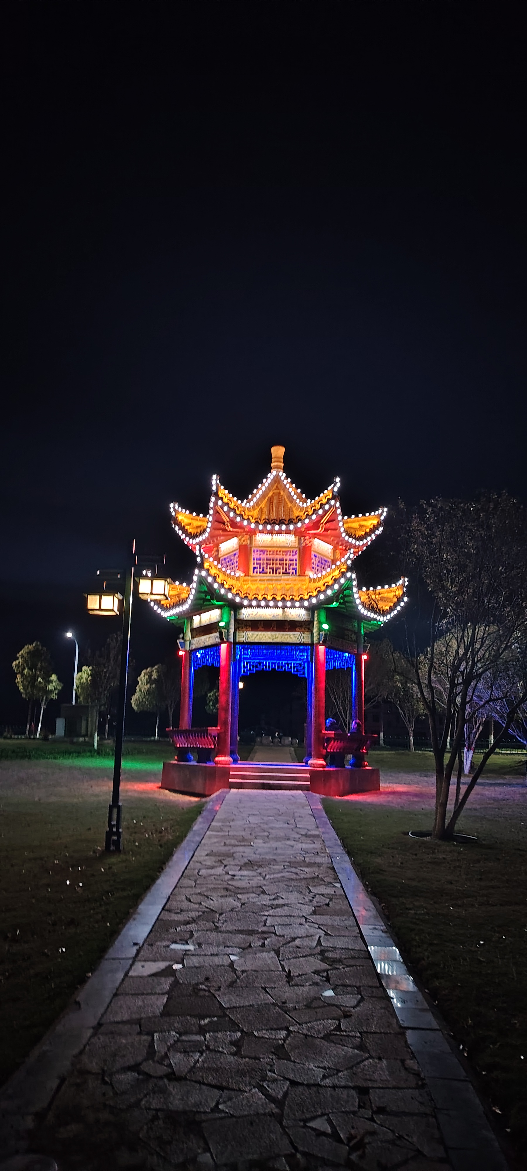 一座装饰华丽的亭子成为了视觉的焦点,红,蓝,黄三色灯光交织,像是夜空