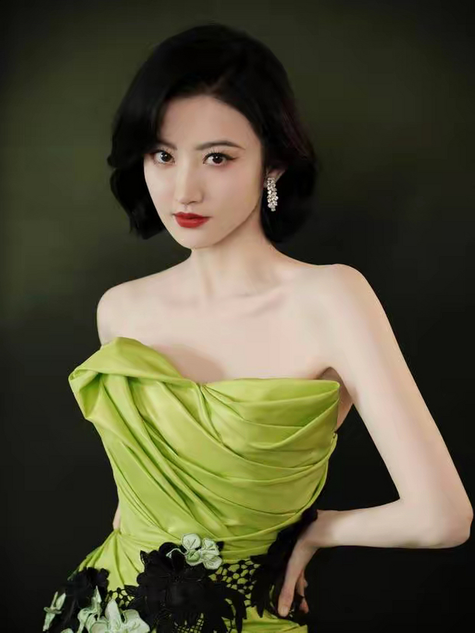 景甜身穿绿色花瓣长裙典雅高贵,手举鲜花明媚动人,露背礼服展示出她