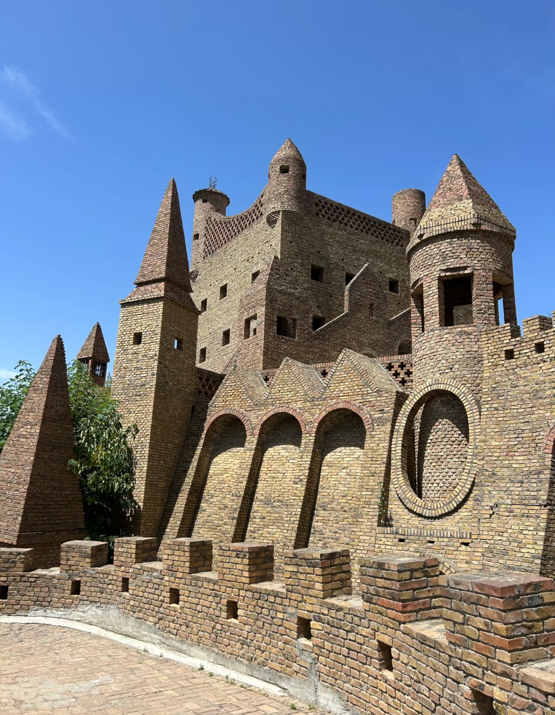 它坐落在山顶上,周围是郁郁葱葱的绿色植被,通往城堡的石路两旁是坚固