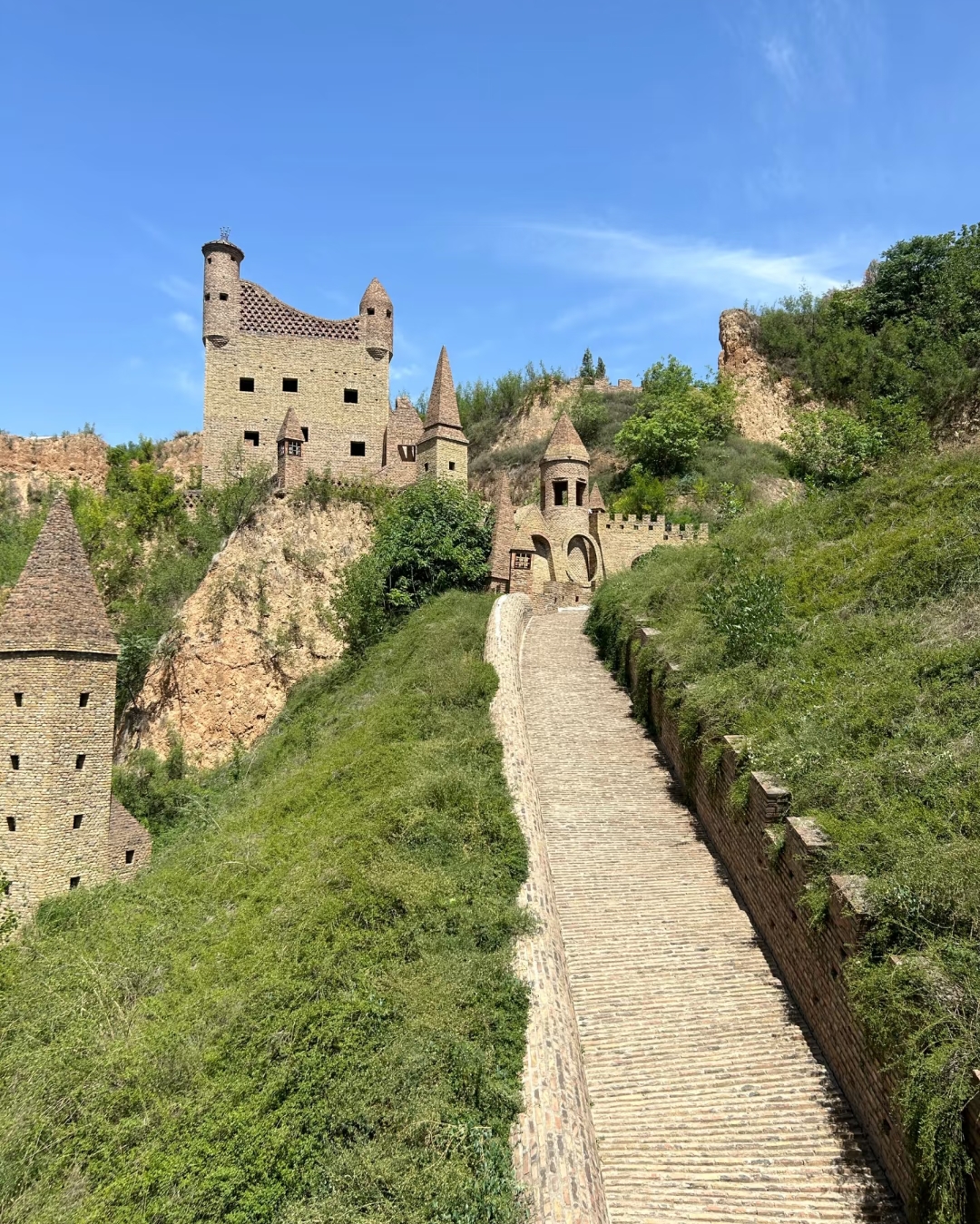 它坐落在山顶上,周围是郁郁葱葱的绿色植被,通往城堡的石路两旁是坚固