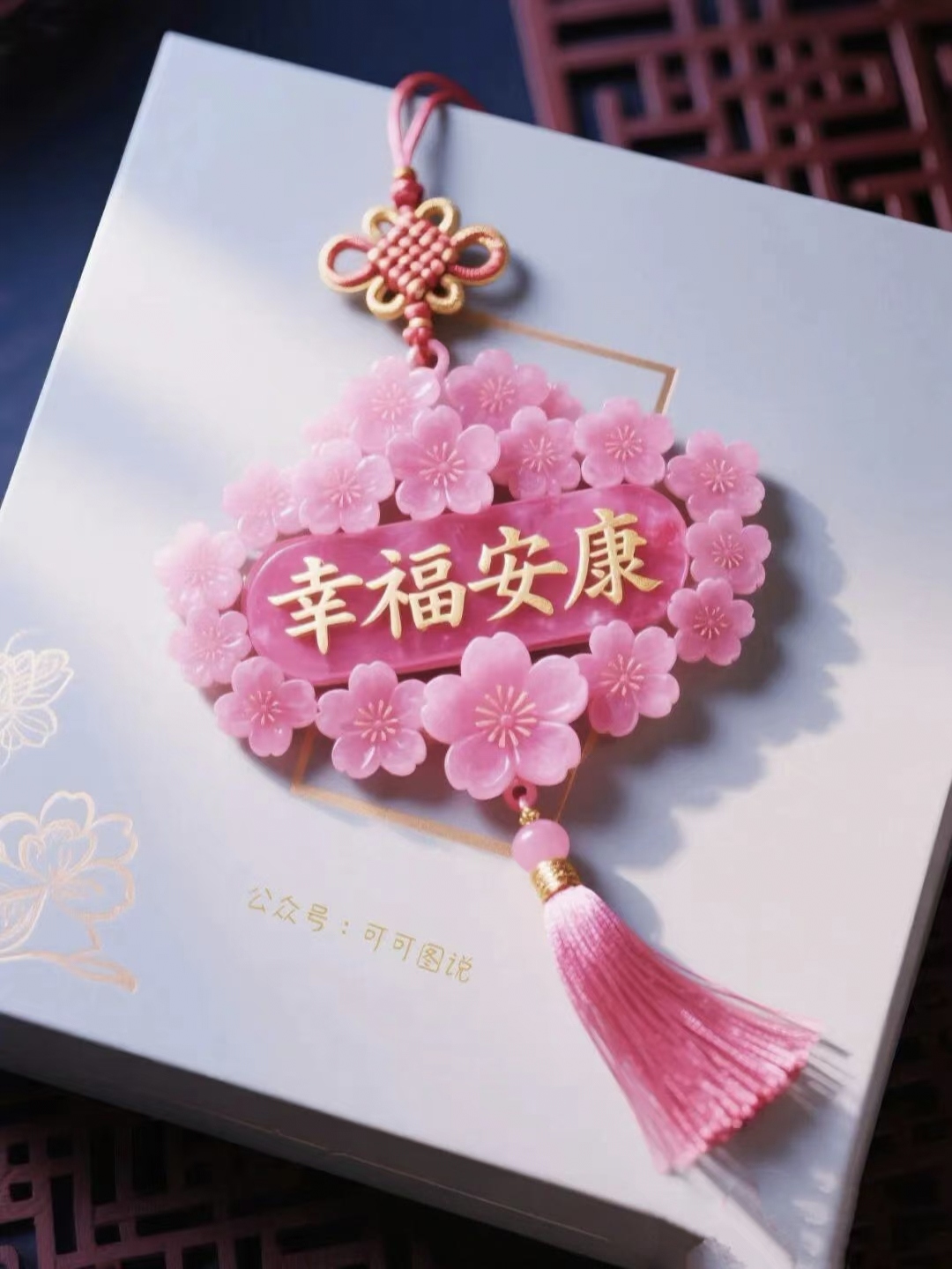 一个粉红色的樱花装饰品,上面刻着"幸福安康"的字样,悬挂在白色背景上