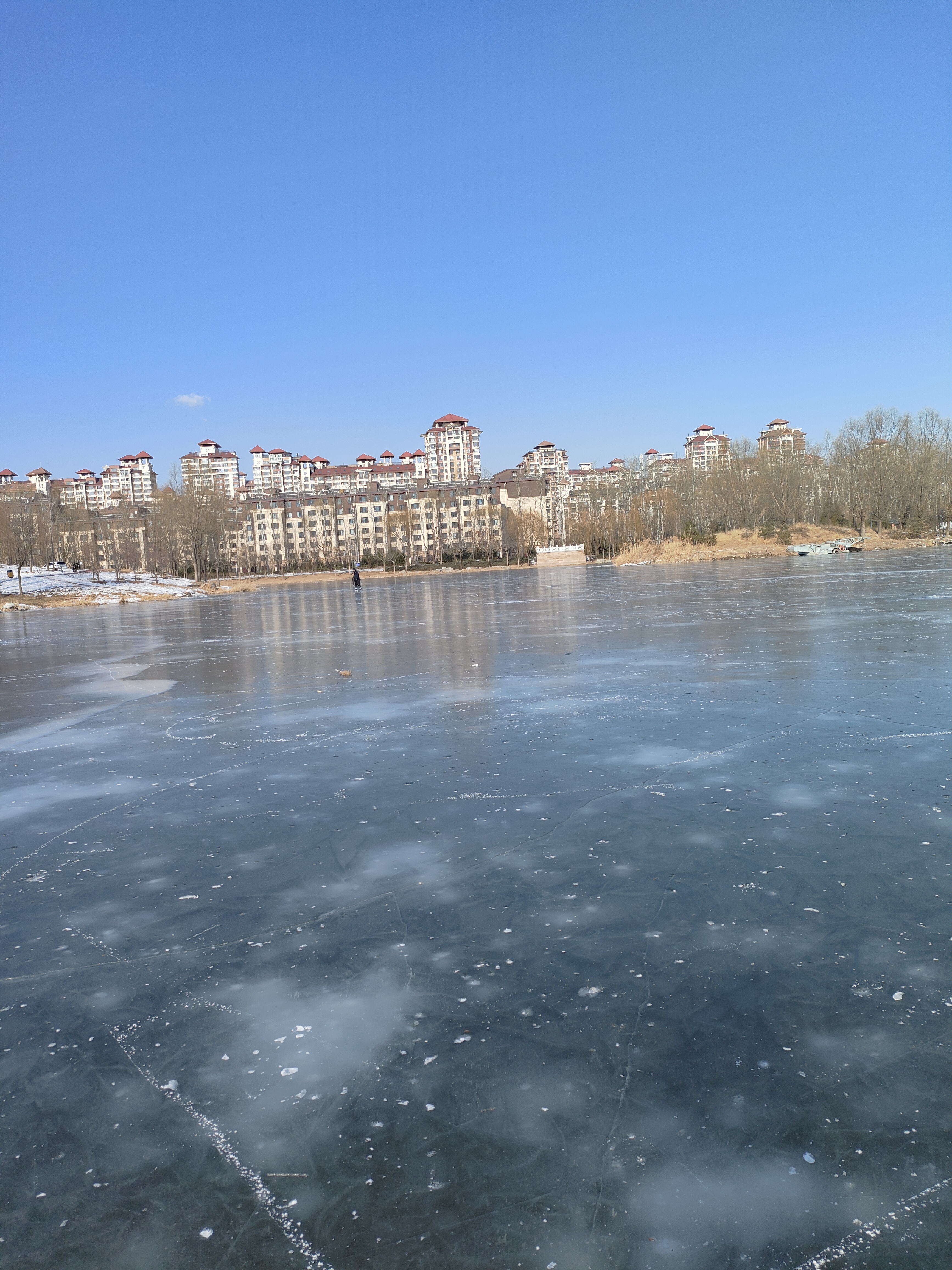 冬日,公园的的河流结冰形成了天然滑冰场,冰封的湖面如一面巨大的镜子