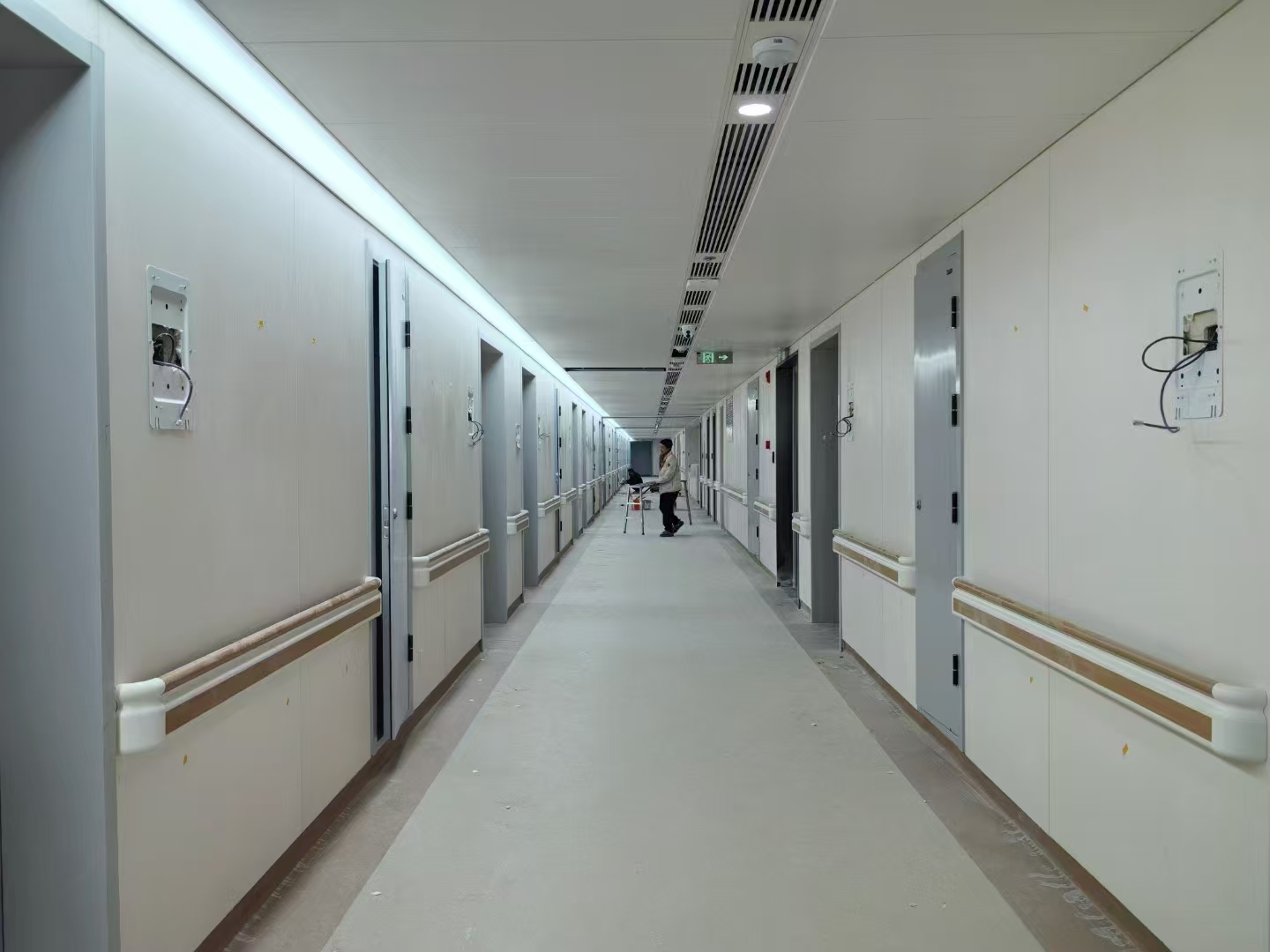 哇,这条长长的走廊看起来像是医院里的一样,两边都是病房门,我得快点