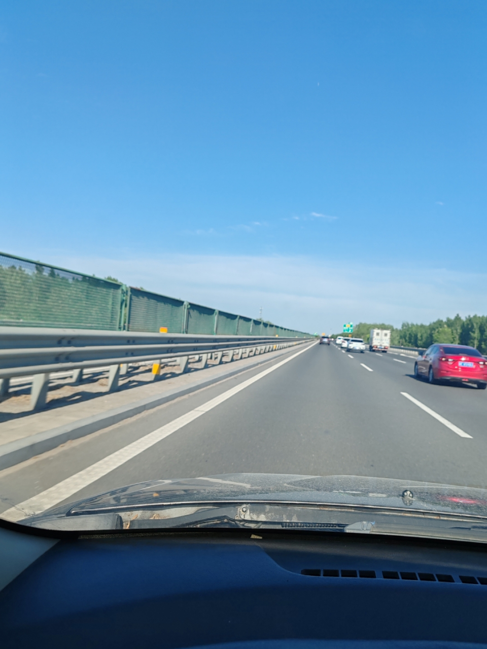 "车辆穿梭于高速公路,后视镜中的天空,树木和建筑交织成一幅流动的