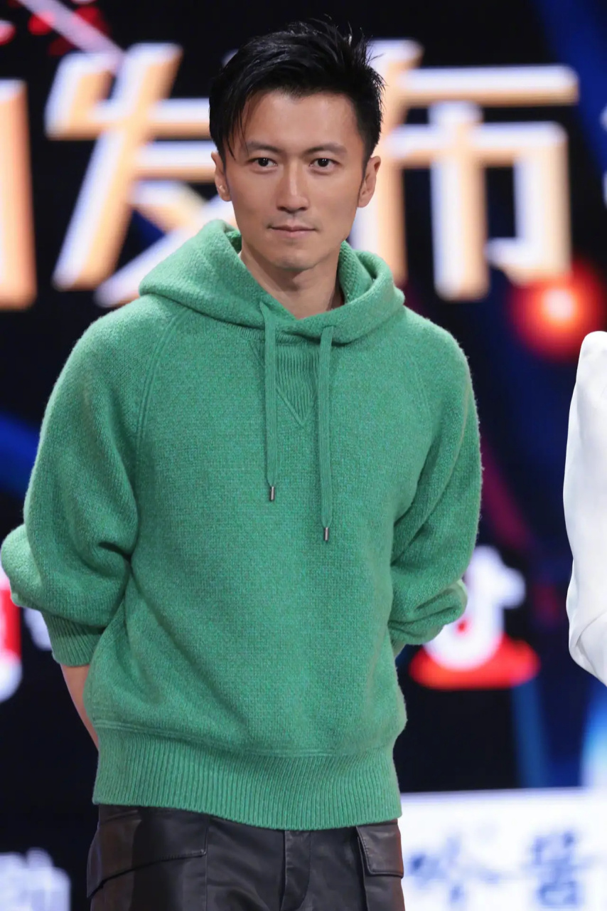 谢霆锋留着标志性的短发,身穿绿色卫衣,搭配黑色工装皮裤,专心致志