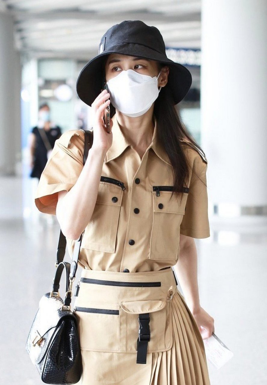 身穿卡其色工装衬衣百褶裙套装搭配黑色渔夫帽和小黑鞋,时髦又帅气