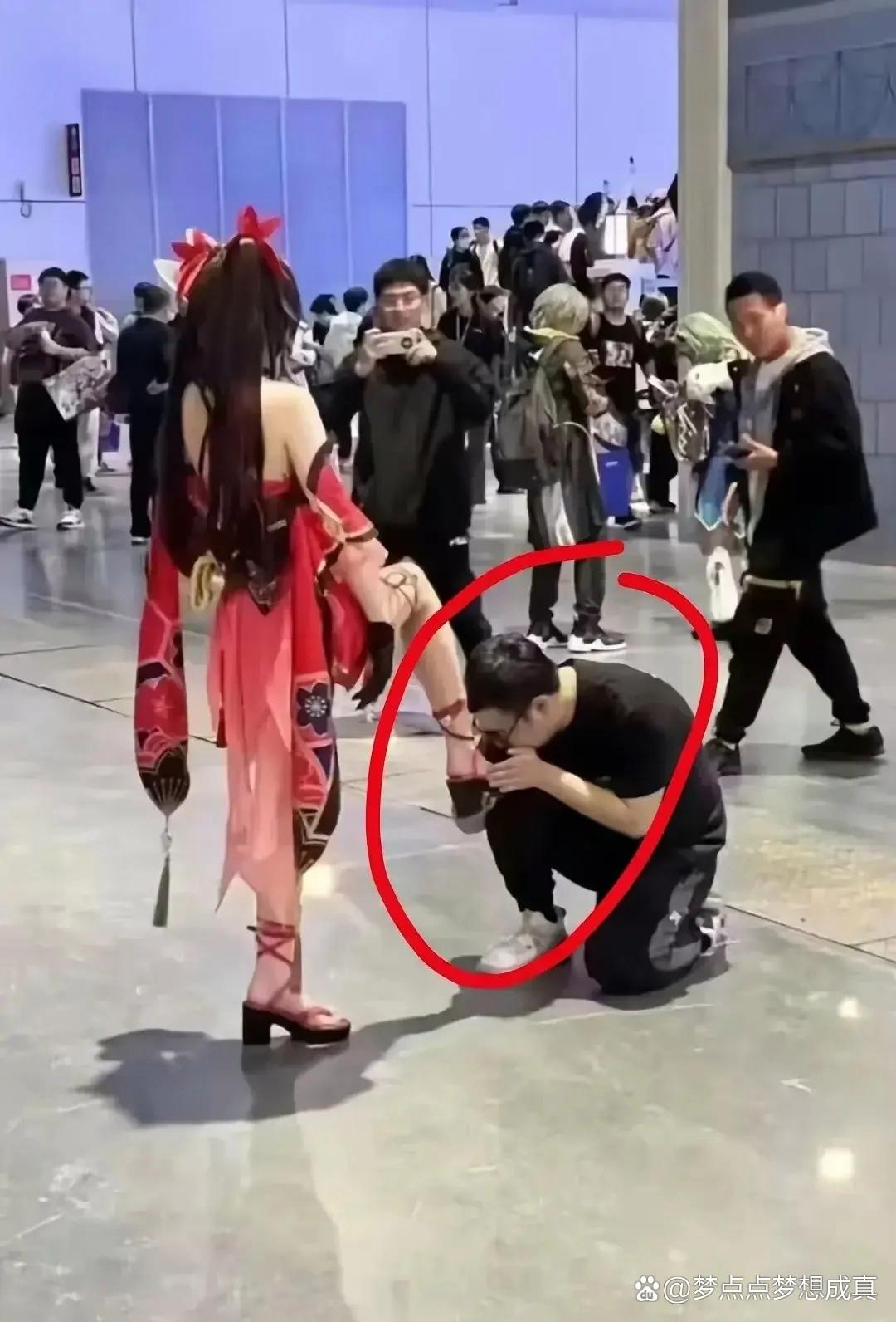 双手捧着美女的一只脚,低头做亲吻状,小伙子这一举动引发路人围观