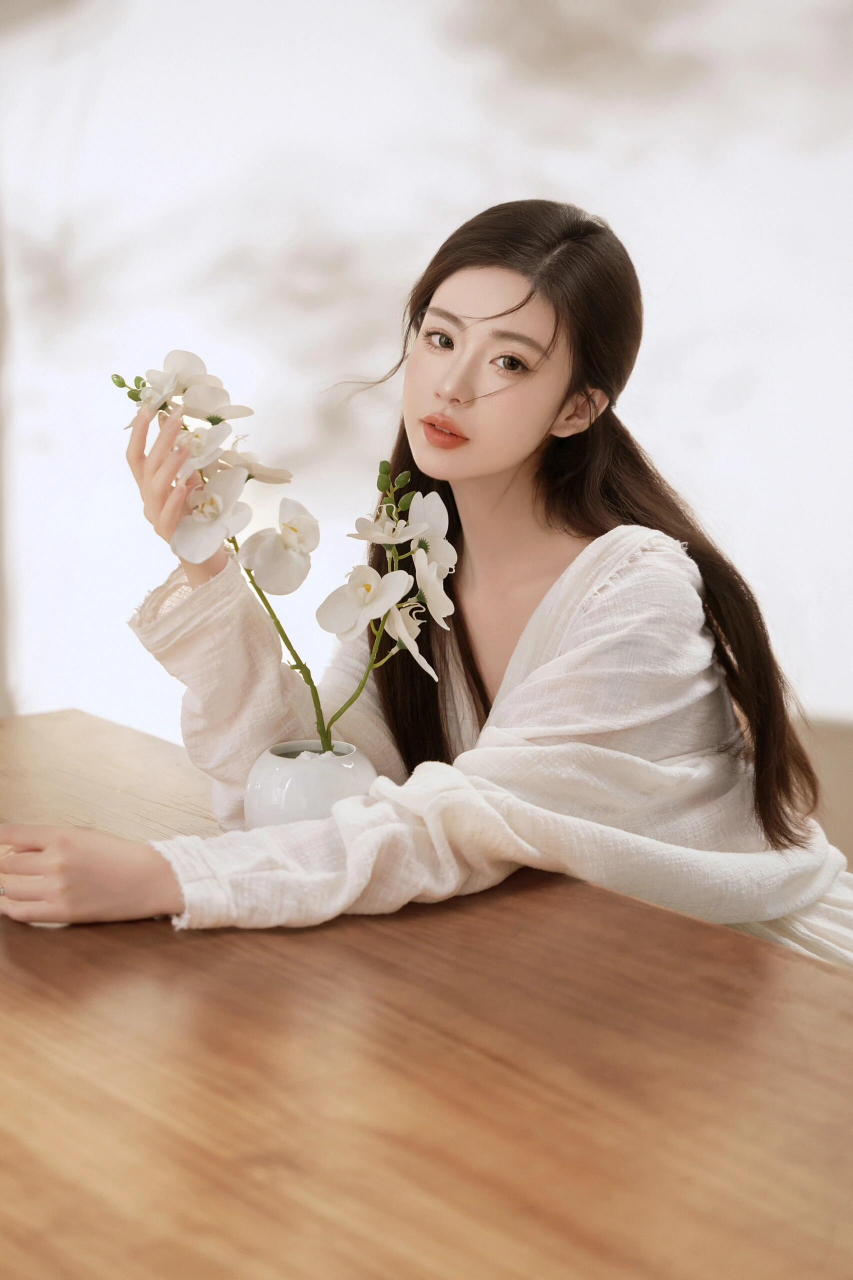 美腿修长,坐在木桌上,旁边是精致的白色花瓶,画面唯美,宛如油画