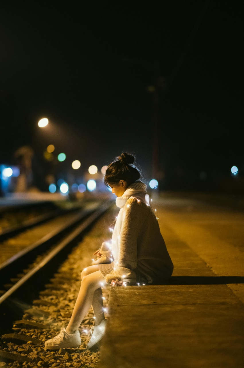 93 夜晚的街道,灯光昏黄,一位穿着毛衣和围巾的女人静静站立.