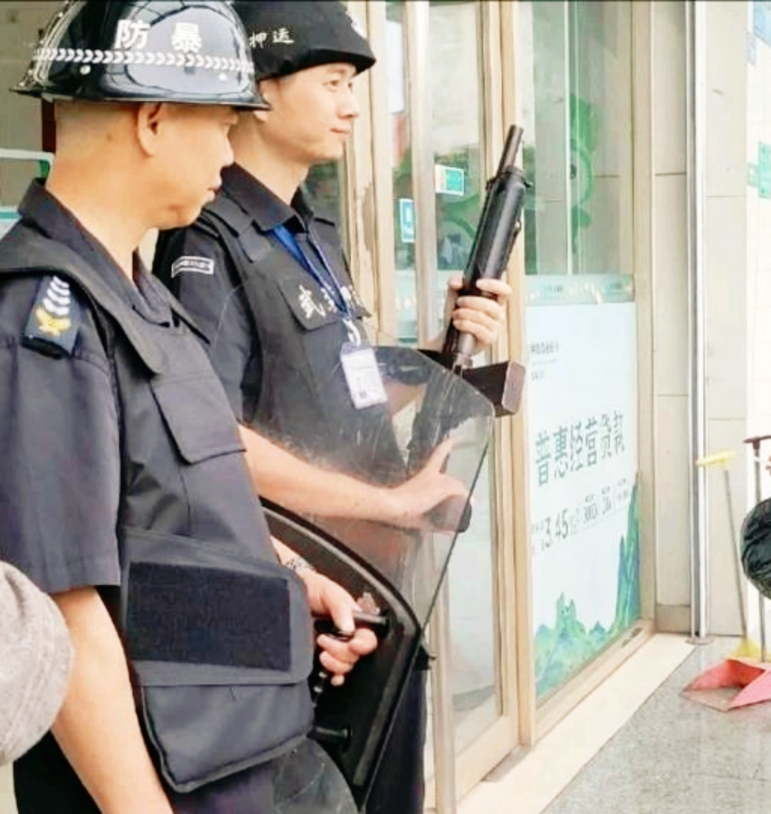 下午时间,在一家银行门口,安保人员严阵以待