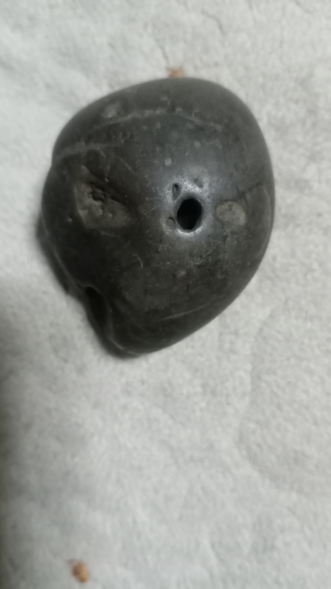 这颗石头有点奇特,中间有个小洞,不知道是天然形成的还是有人工加工的