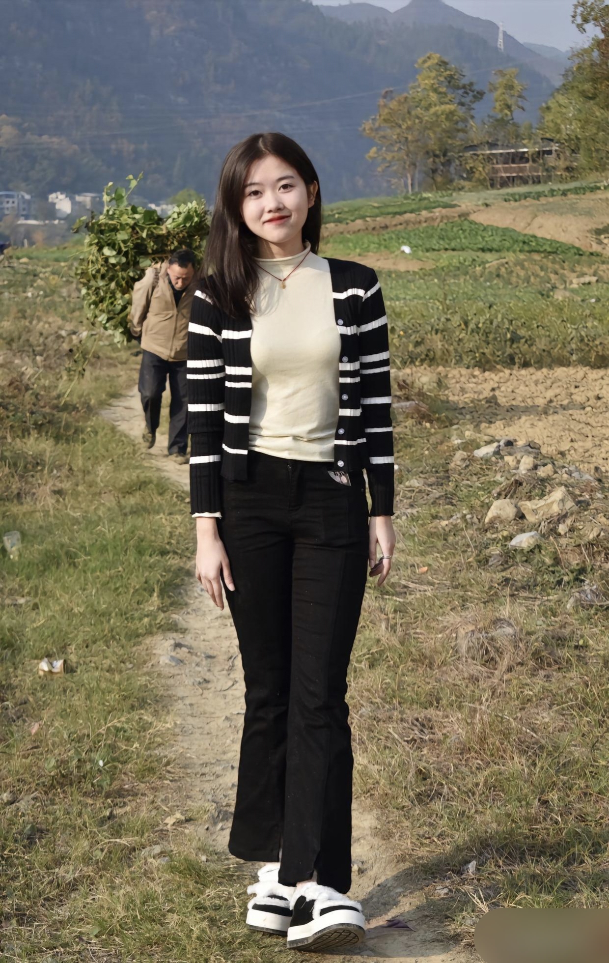 乡间的小路上,她身着经典的黑白条纹开衫,内搭米色高领毛衣,简约而不