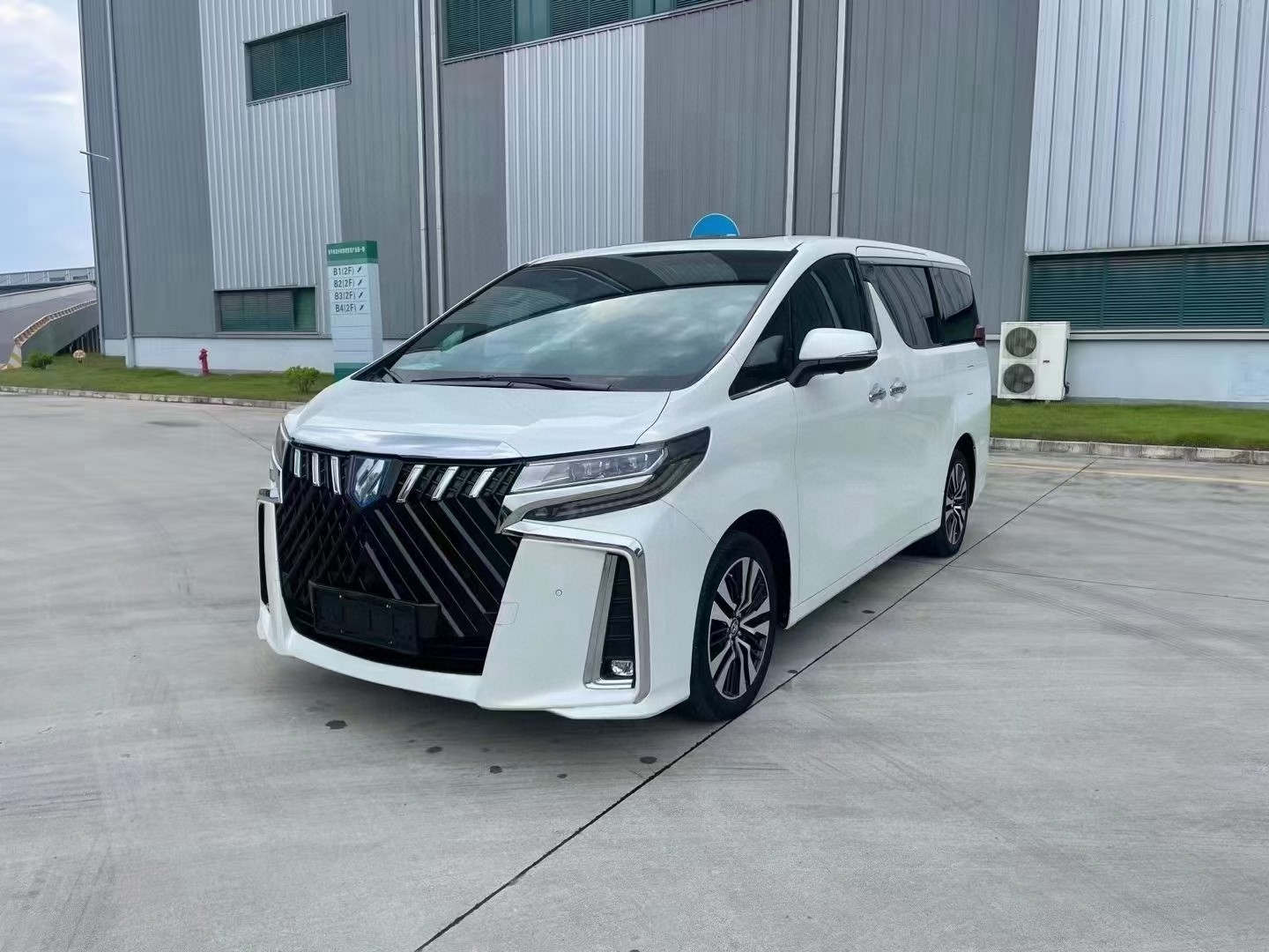 白色丰田alphard mpv亮相,现代设计配蓝色"toyota"标,背景建筑现"