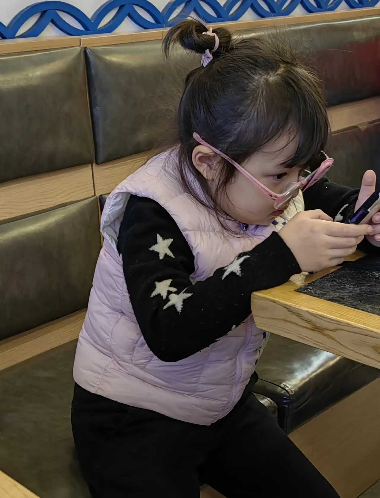 昨天我在一家便餐店里看到一位4岁大的小女孩在玩手机只见她双手捧