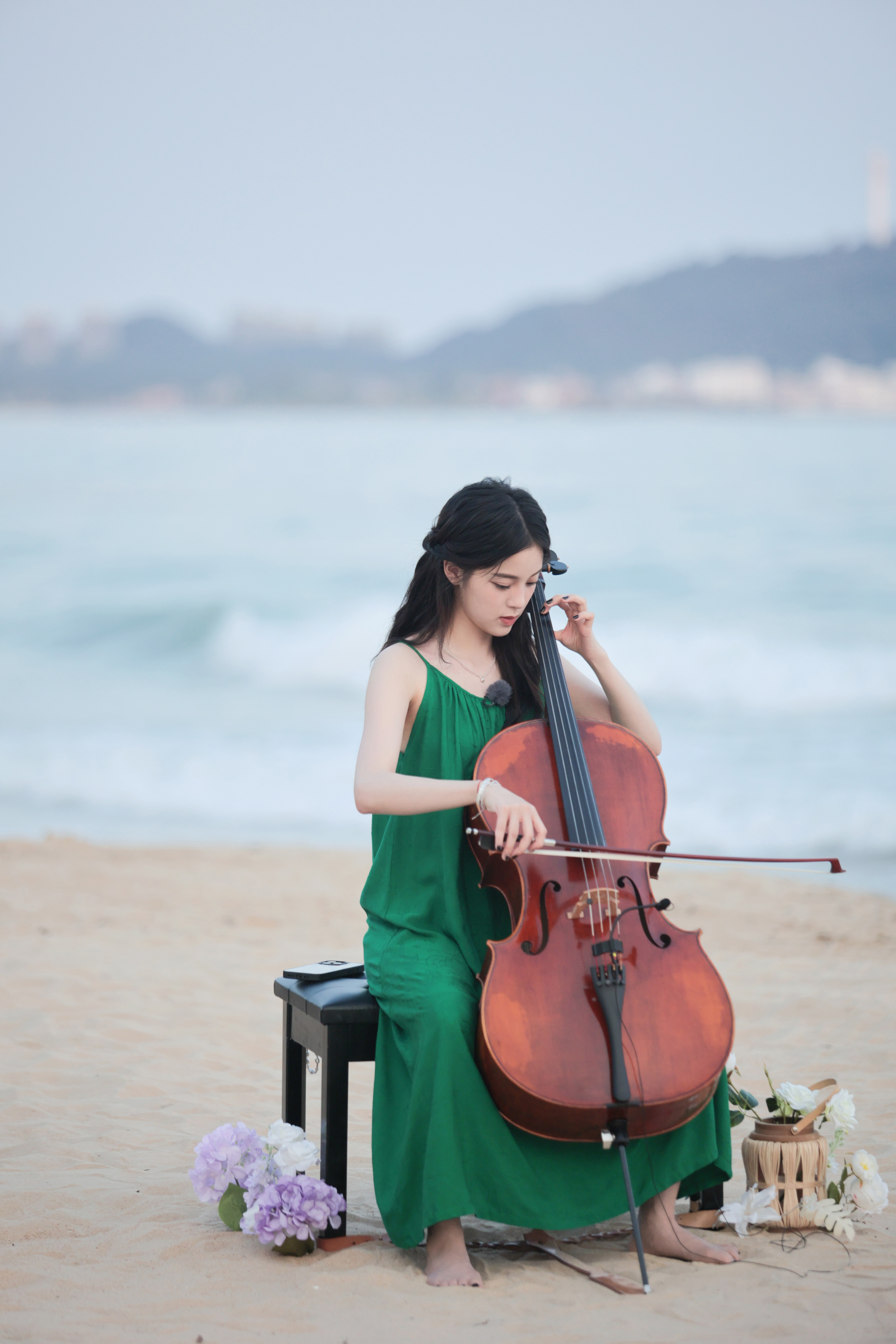 欧阳娜娜在海边音乐会上,身着绿色吊带裙优雅演奏大提琴,不仅展示了她