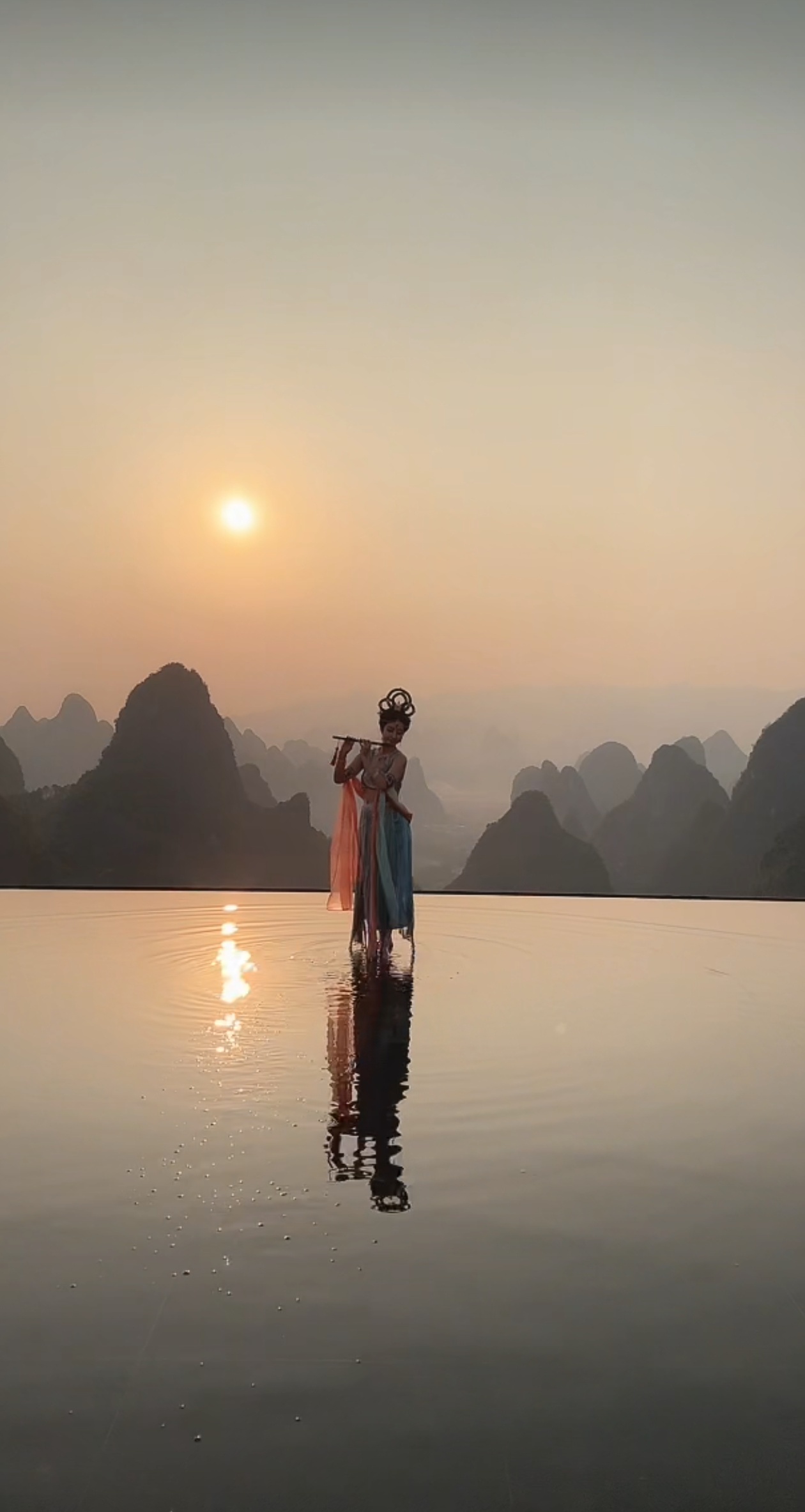 群峰倒影青螺现,一水涵空碧玉流. 仙子凌波舒彩袖,霓裳映日焕云绸