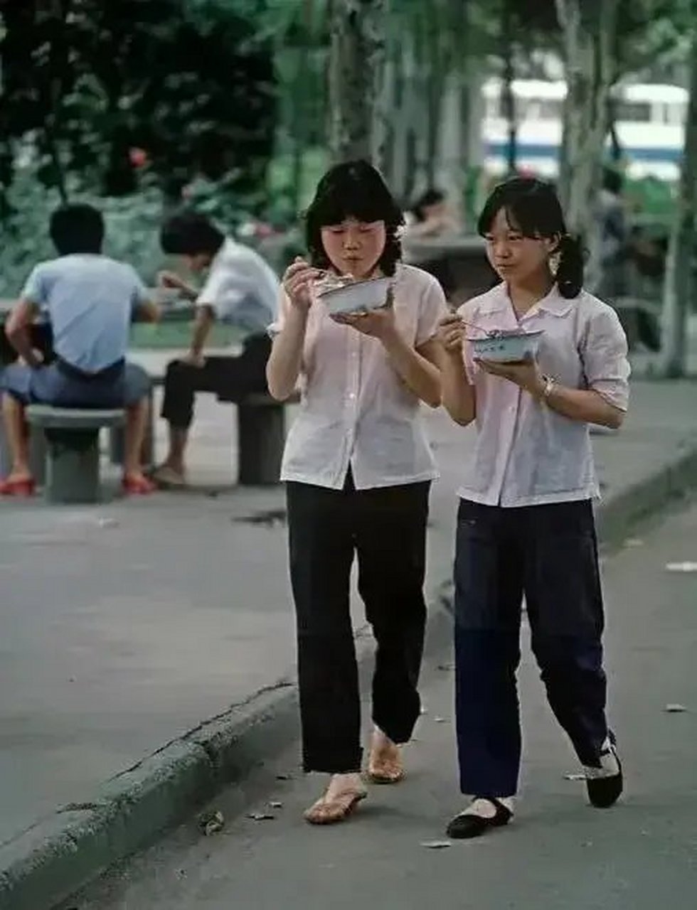 这张照片拍摄于1983年,成都川棉厂两名女工人端着碗,在厂区里边走边吃