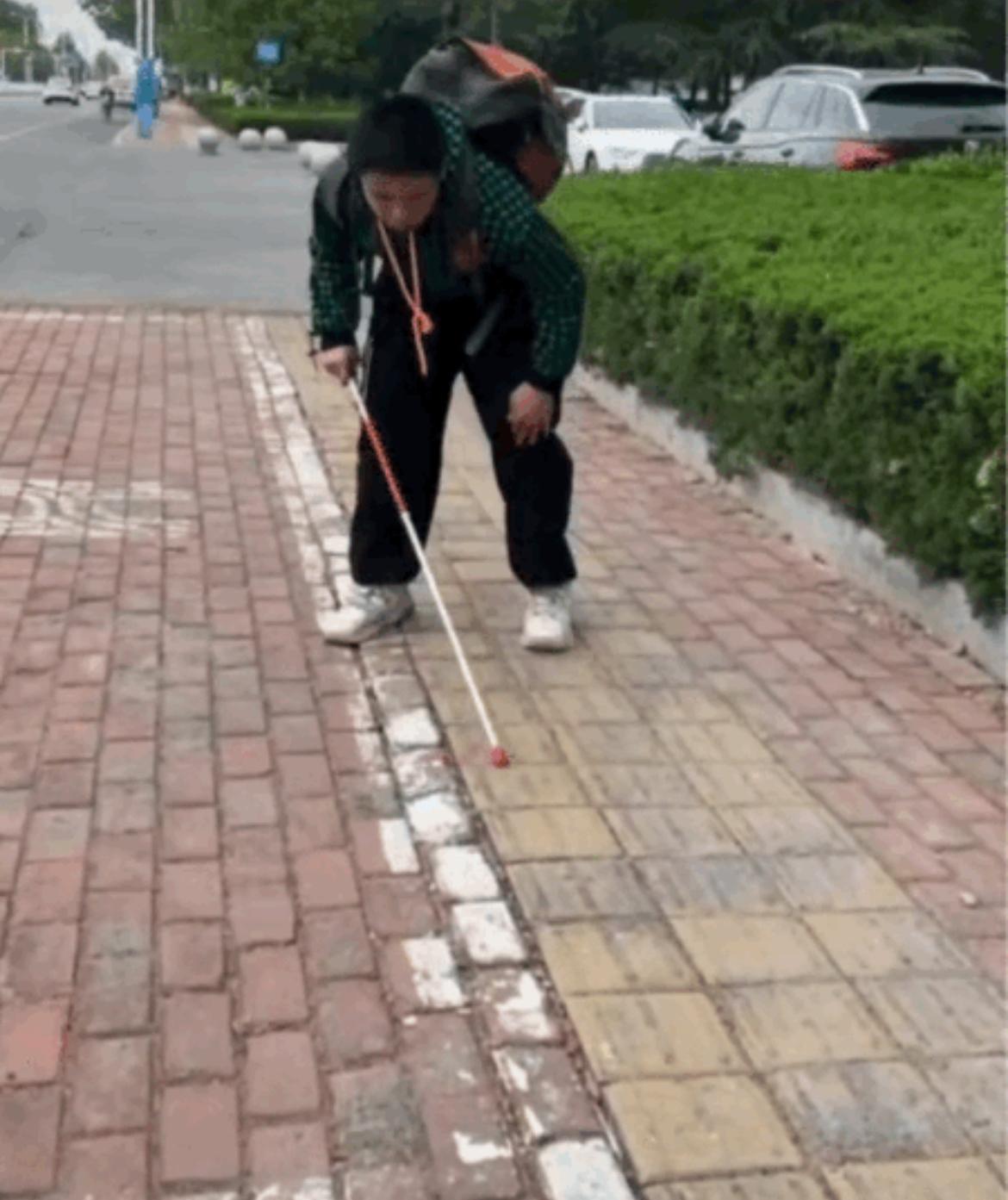 盲人小孩第一次出门,妈妈一直跟在身后,这边盲道年数太久已经磨平了