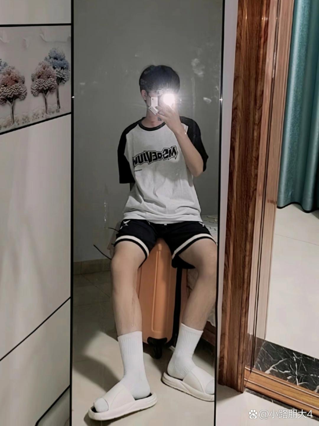 " 身穿黑色和白色运动服的男生,坐在镜子前自拍
