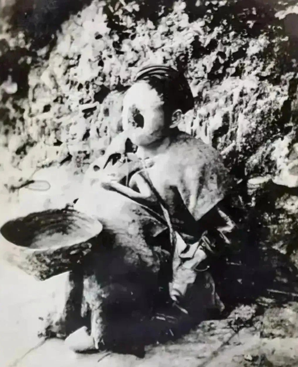 这张照片拍摄于1917年,四川遂宁,一处偏僻的小路边上,一个"麻风病人"