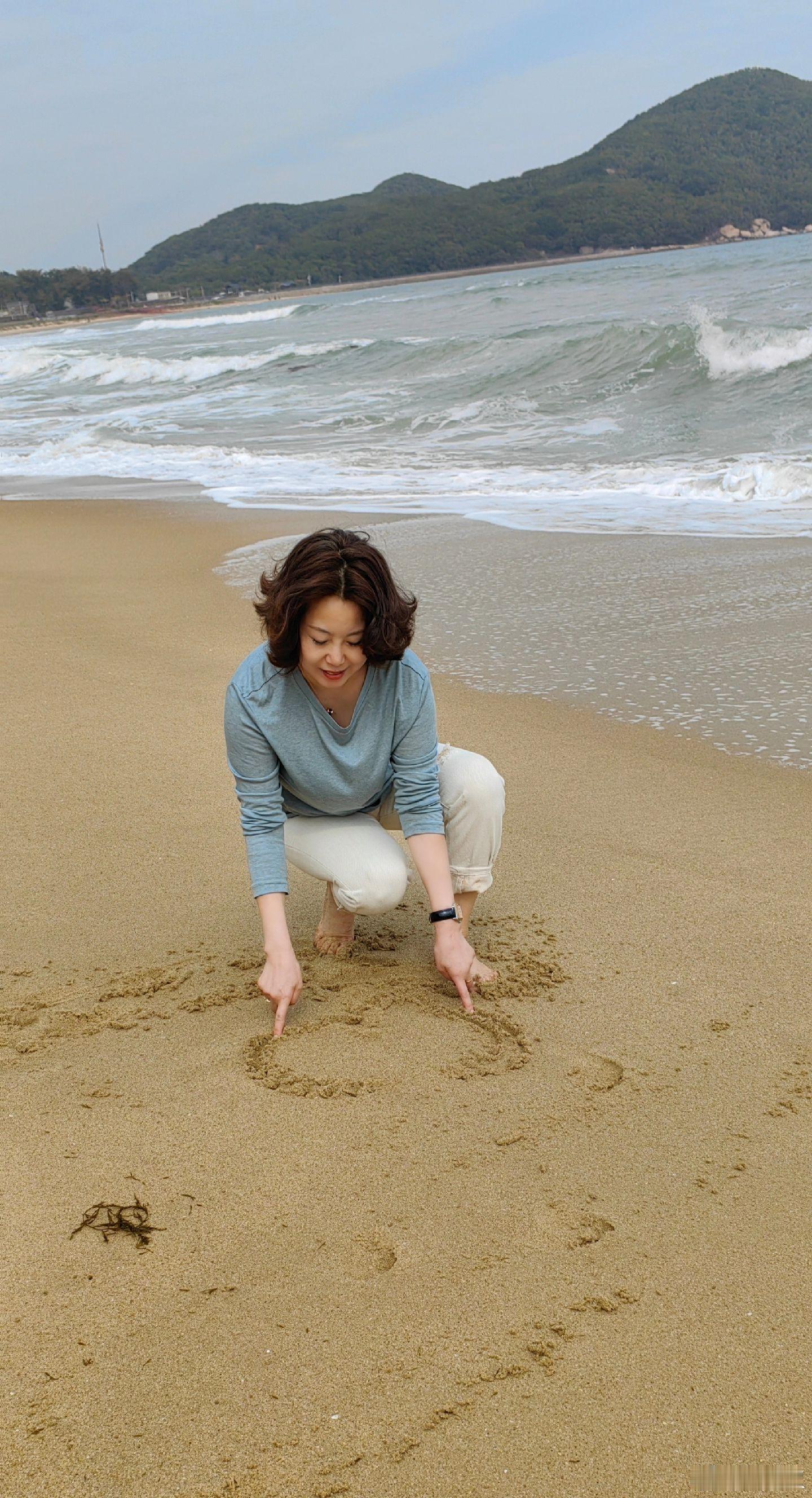 孩子般快乐,时而奔跑着追逐海水玩耍,发出欢快的笑声;时而蹲在沙滩上