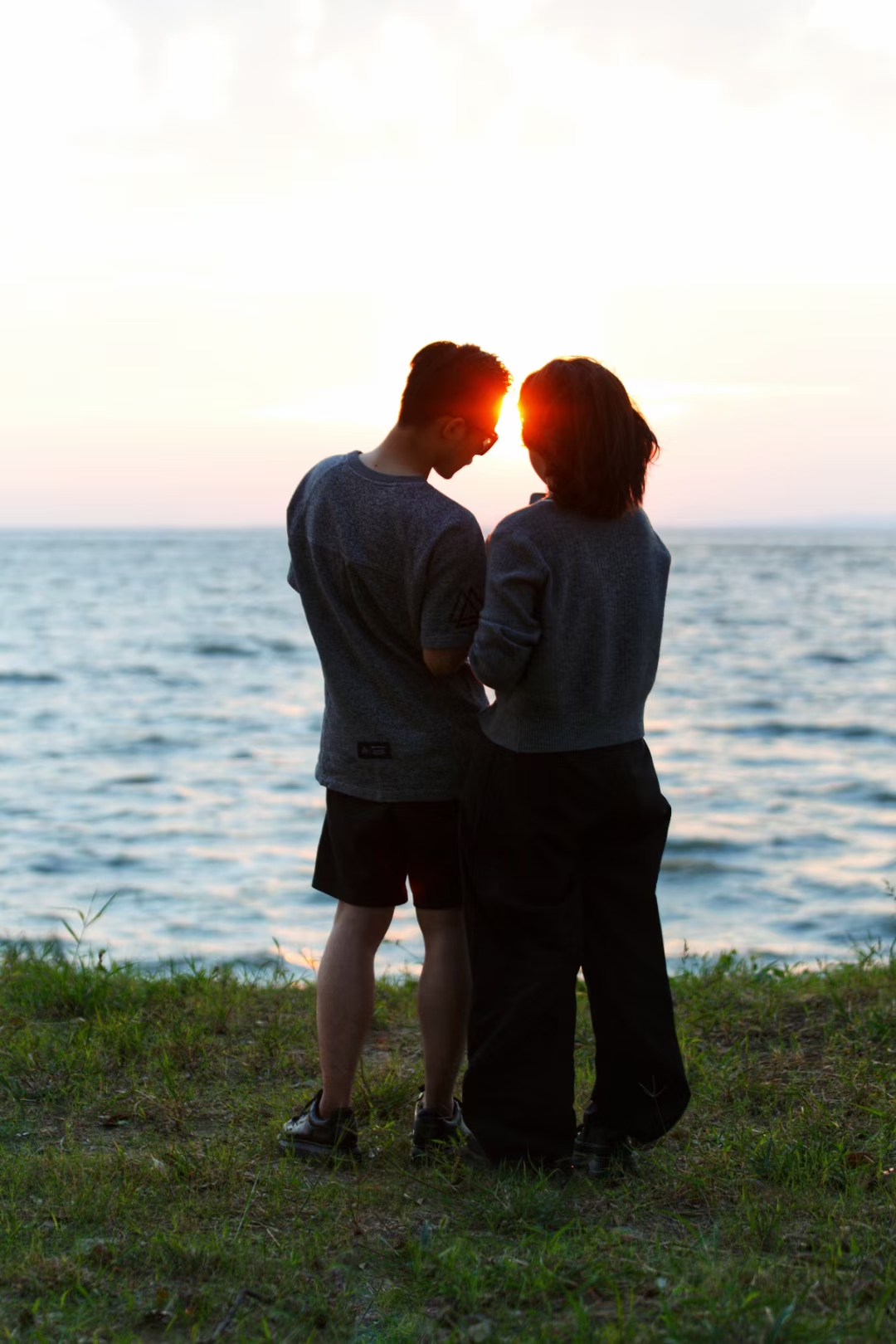 93落日余晖下,有一对背影恋人,面朝大海,背对尘世.