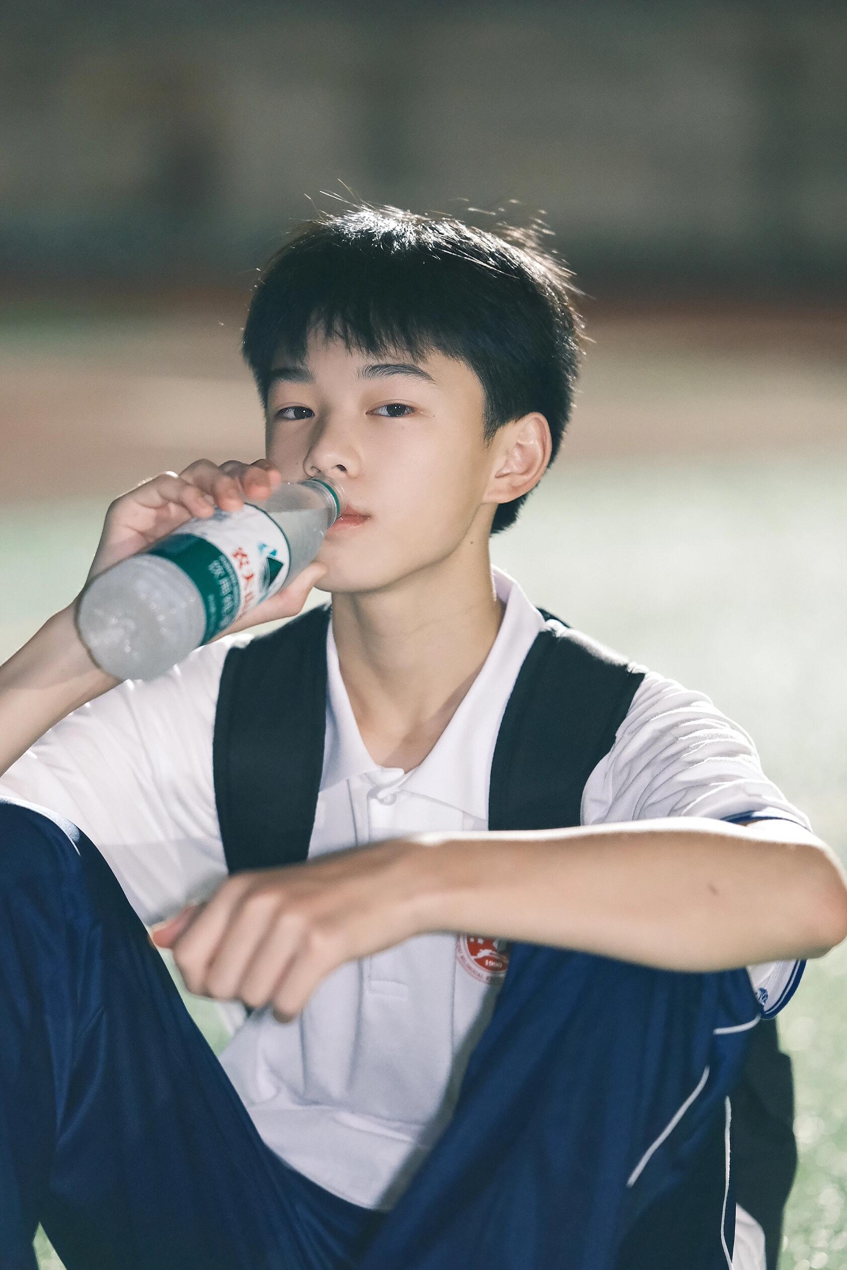 稚嫩的男高中生 放学后的宁静时刻,坐在草地上,享受片刻的闲暇.