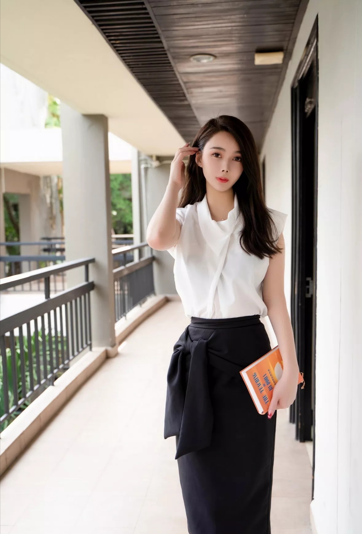 走廊上,她安静地站在那里,白衬衫与黑裙子简约大方,手中紧握着书和笔