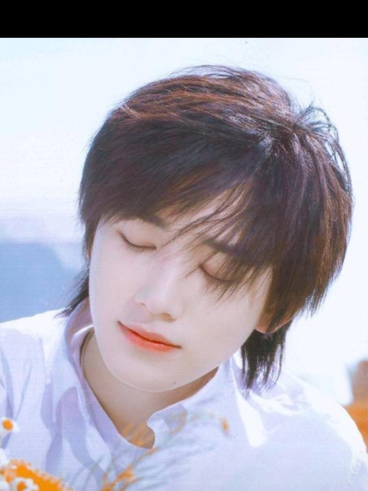 宋亚轩手捧鲜花,站在绿树成荫的草坪上,笑容灿烂如花.