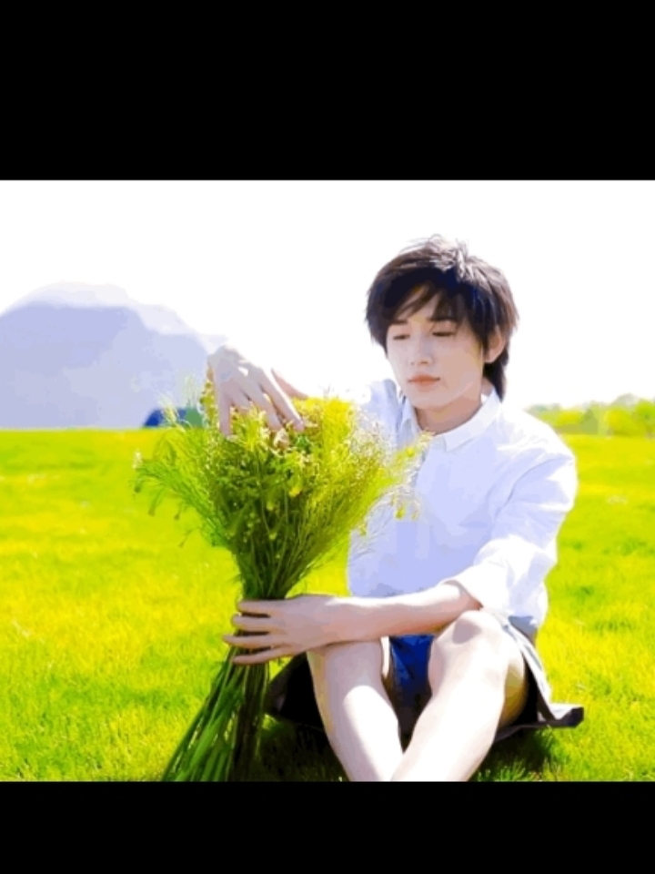 宋亚轩手捧鲜花,站在绿树成荫的草坪上,笑容灿烂如花.