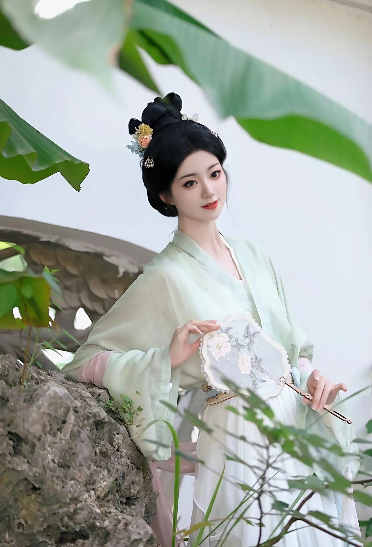 古风美人,一袭白衣胜雪,手持团扇,漫步于园林之中,宛如画中仙子.