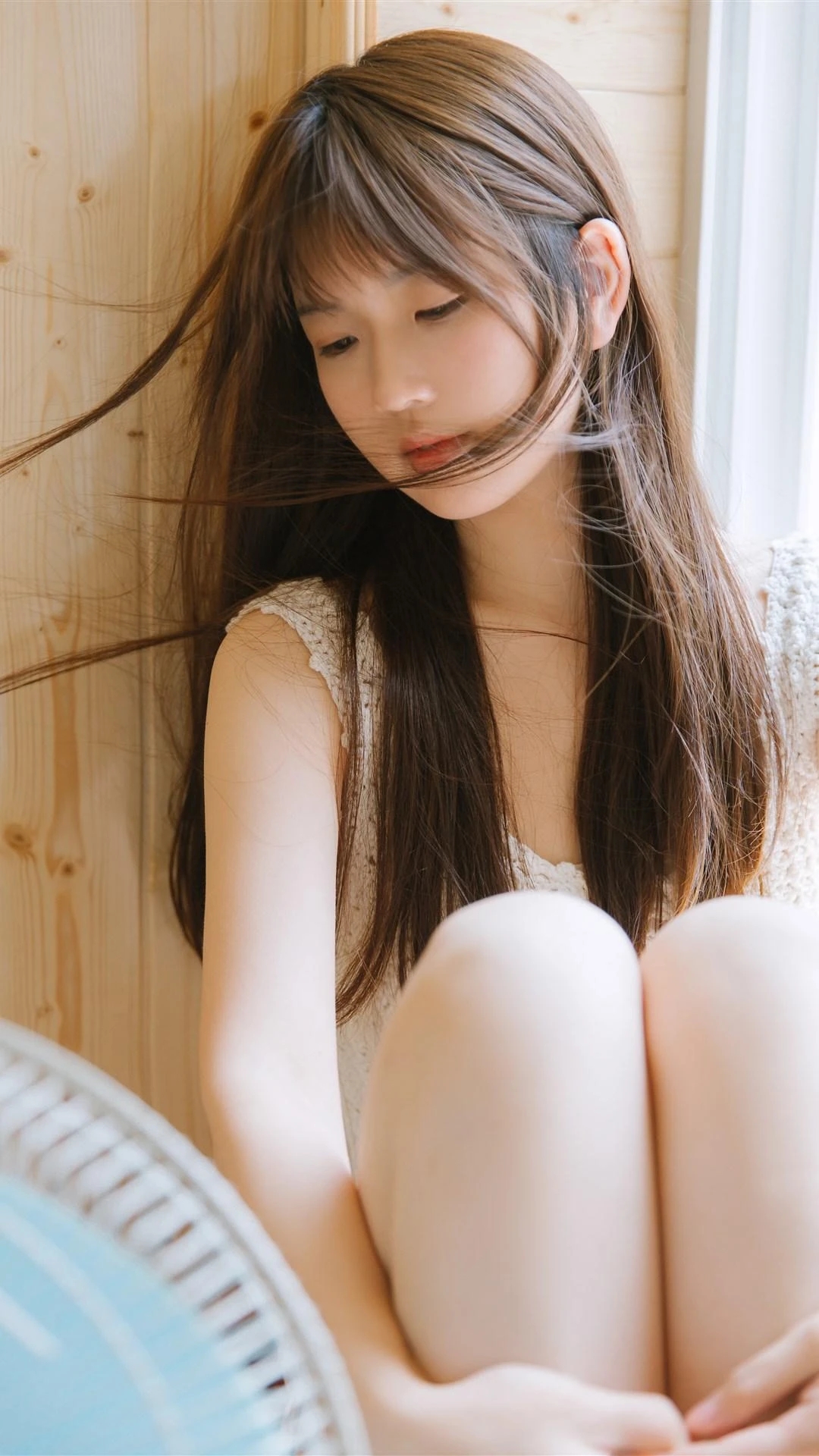 女孩站在窗边,阳光洒在她的白毛衣上,微风轻轻吹起她的发梢,她回眸