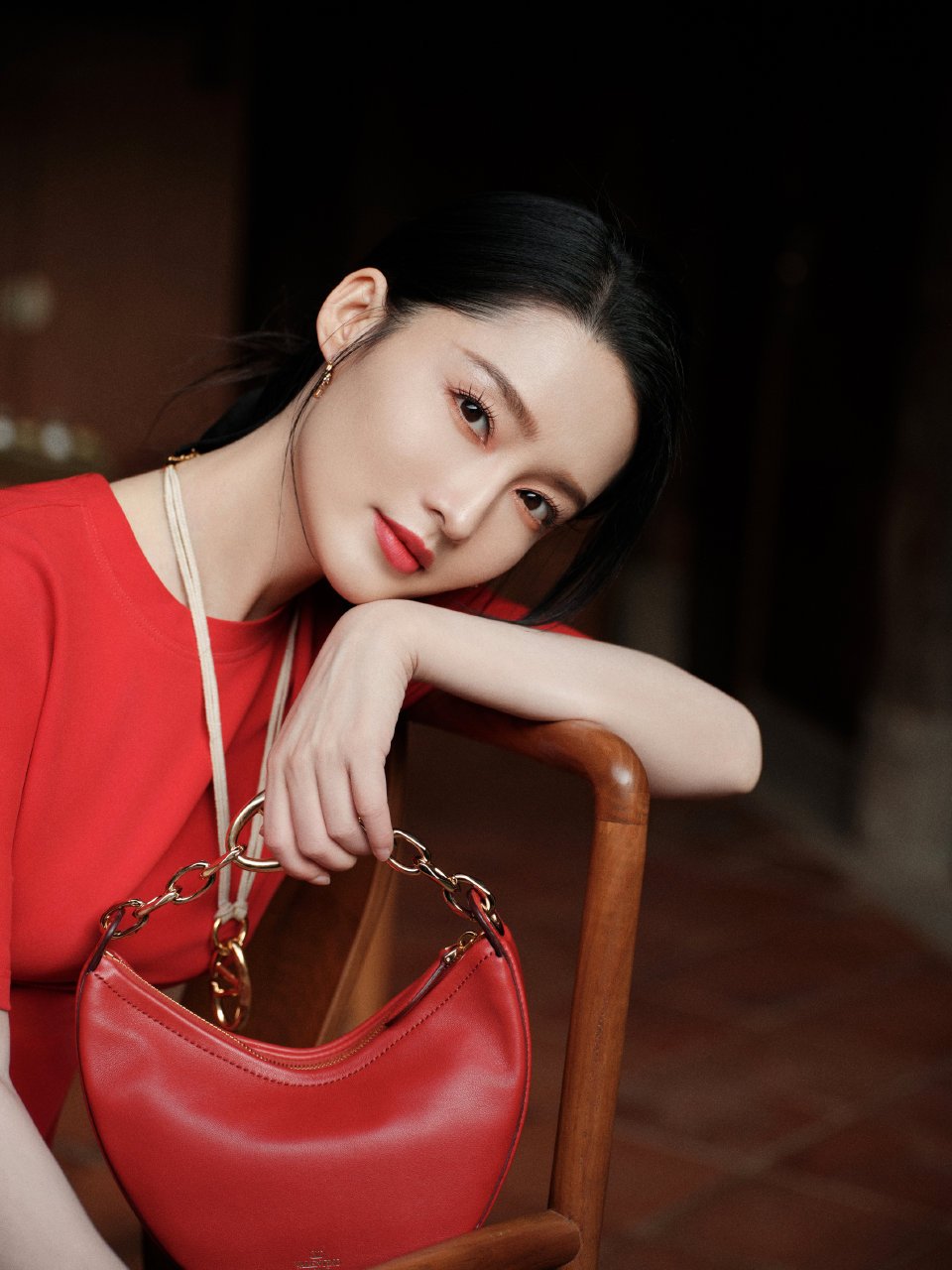 李沁的红色手提包点缀着整个暗色调背景,就像生活中的一抹亮色,提醒