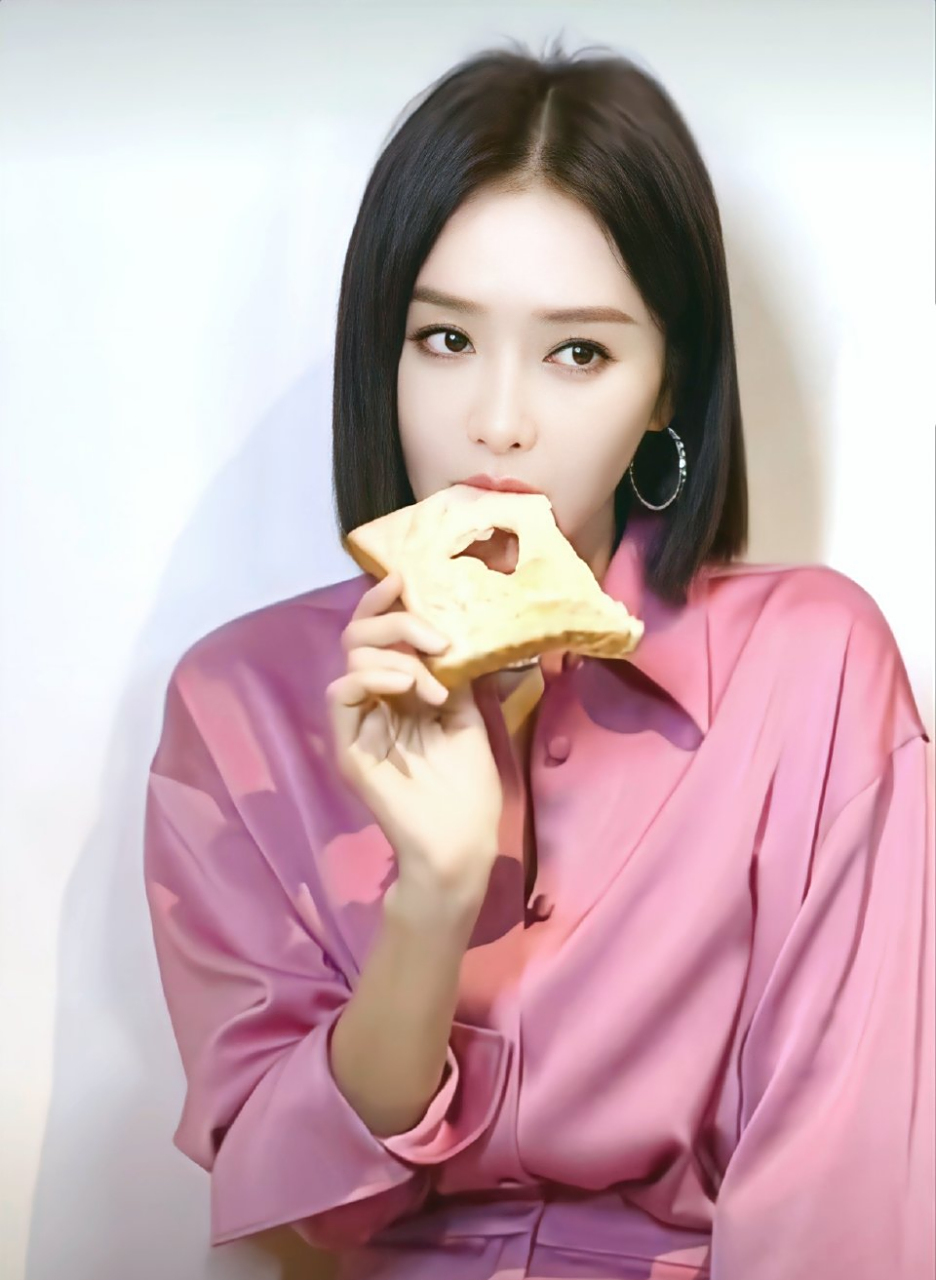 秦岚身着粉色衬衣边吃面包边摆拍,彰显出俏皮可爱的氛围感,而她的双眸