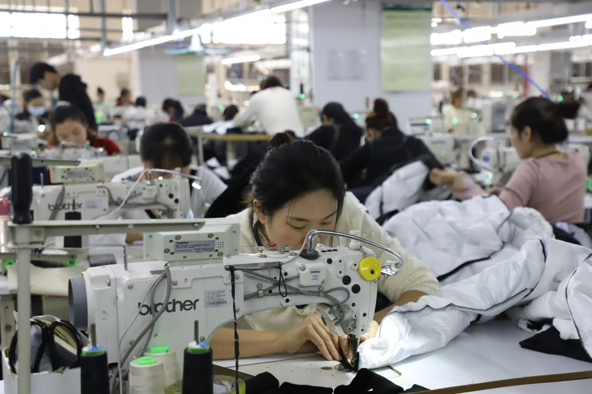 服饰有限责任公司车间里,人欢机唱,200多名职工剪裁熨烫,赶制订单服装