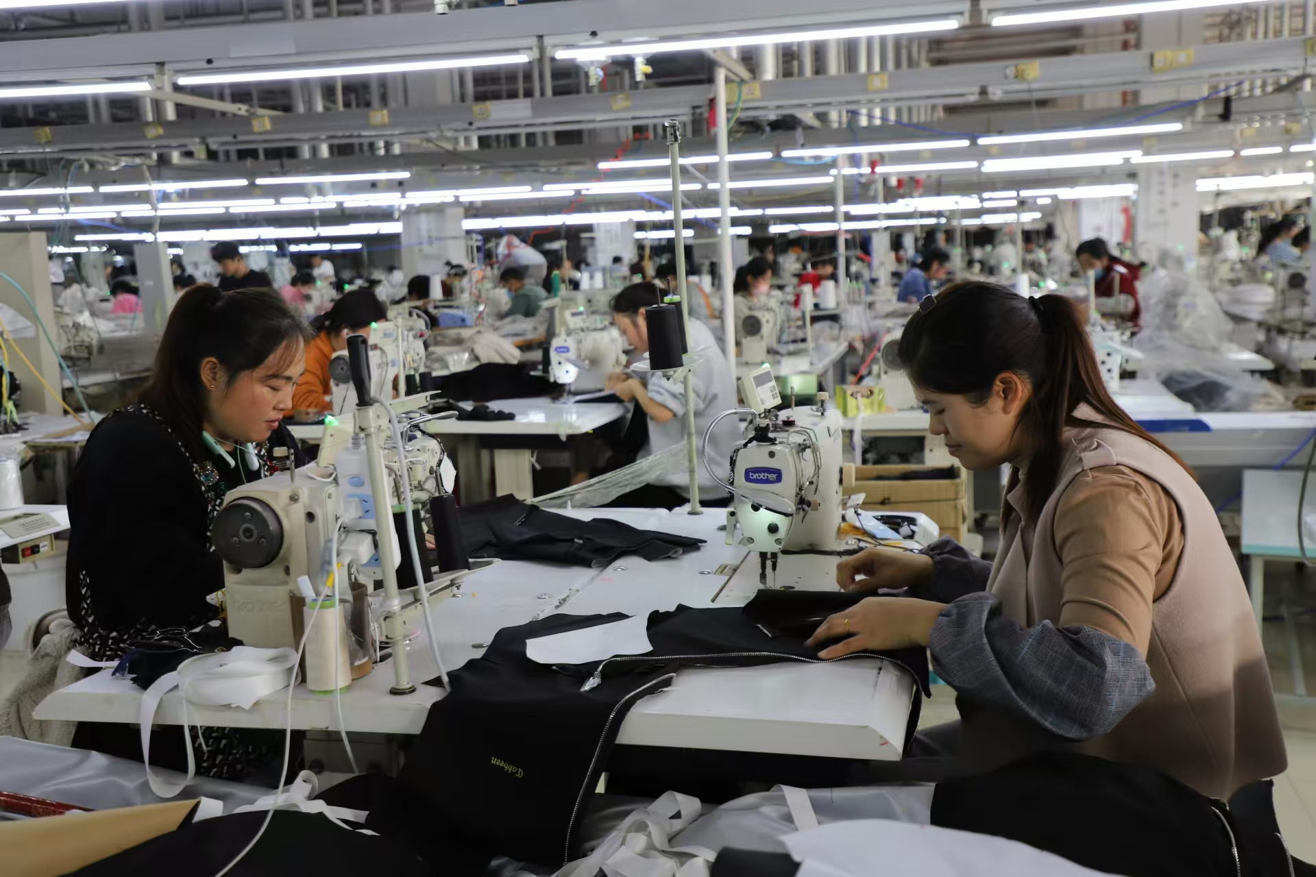 服饰有限责任公司车间里,人欢机唱,200多名职工剪裁熨烫,赶制订单服装