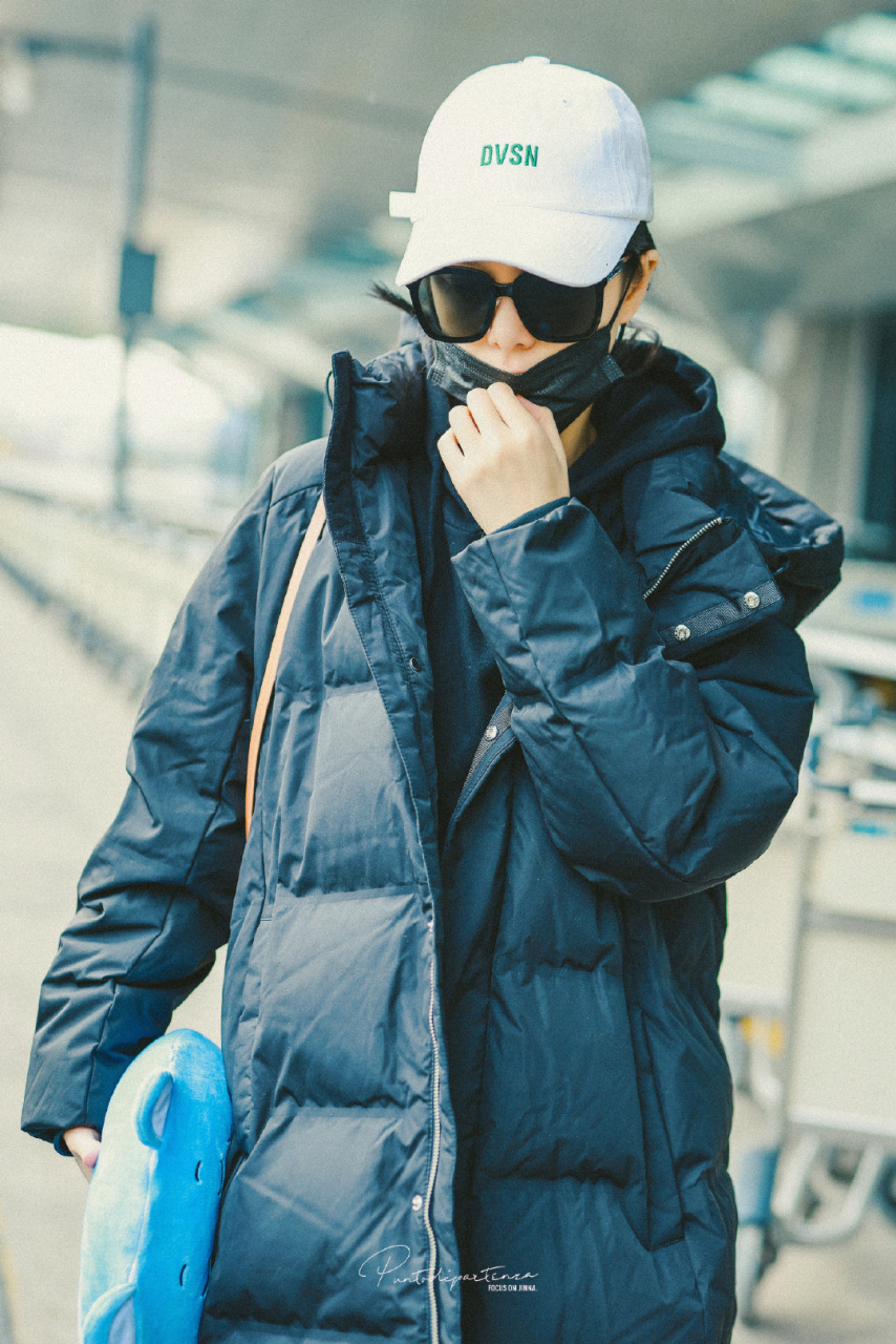 春运最in街拍# 傅菁机场街拍,身穿黑色长款羽绒服内搭连帽卫衣,简约