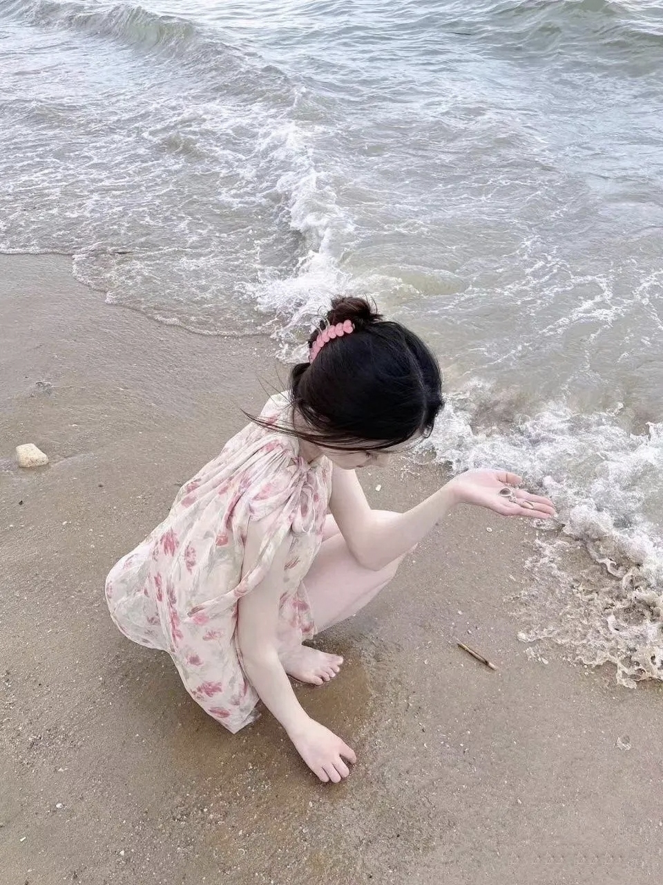 跨年创作挑战赛#美女图鉴 沙滩上,一个小女孩蹲着,玩着水,淡粉色的
