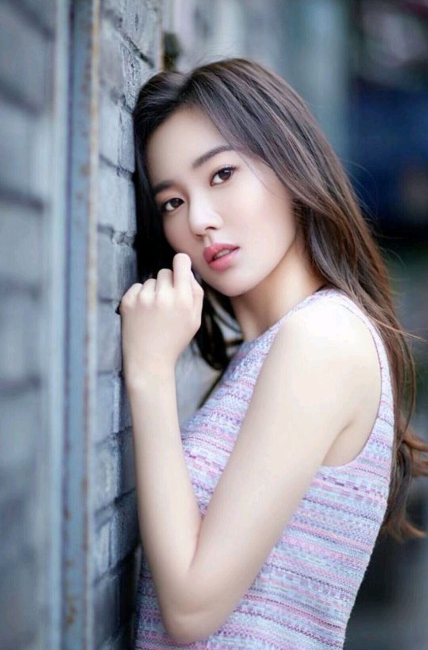 江铠同倚靠在砖墙边,长发温柔地顺着脸颊滑落,侧颜美得让人心动