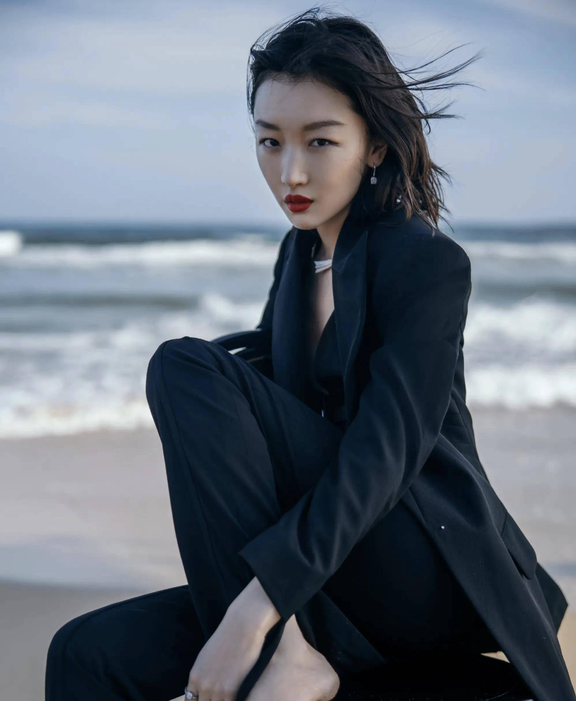 周冬雨坐在海边礁石上,海风吹起她的发丝,红唇格外引人注目